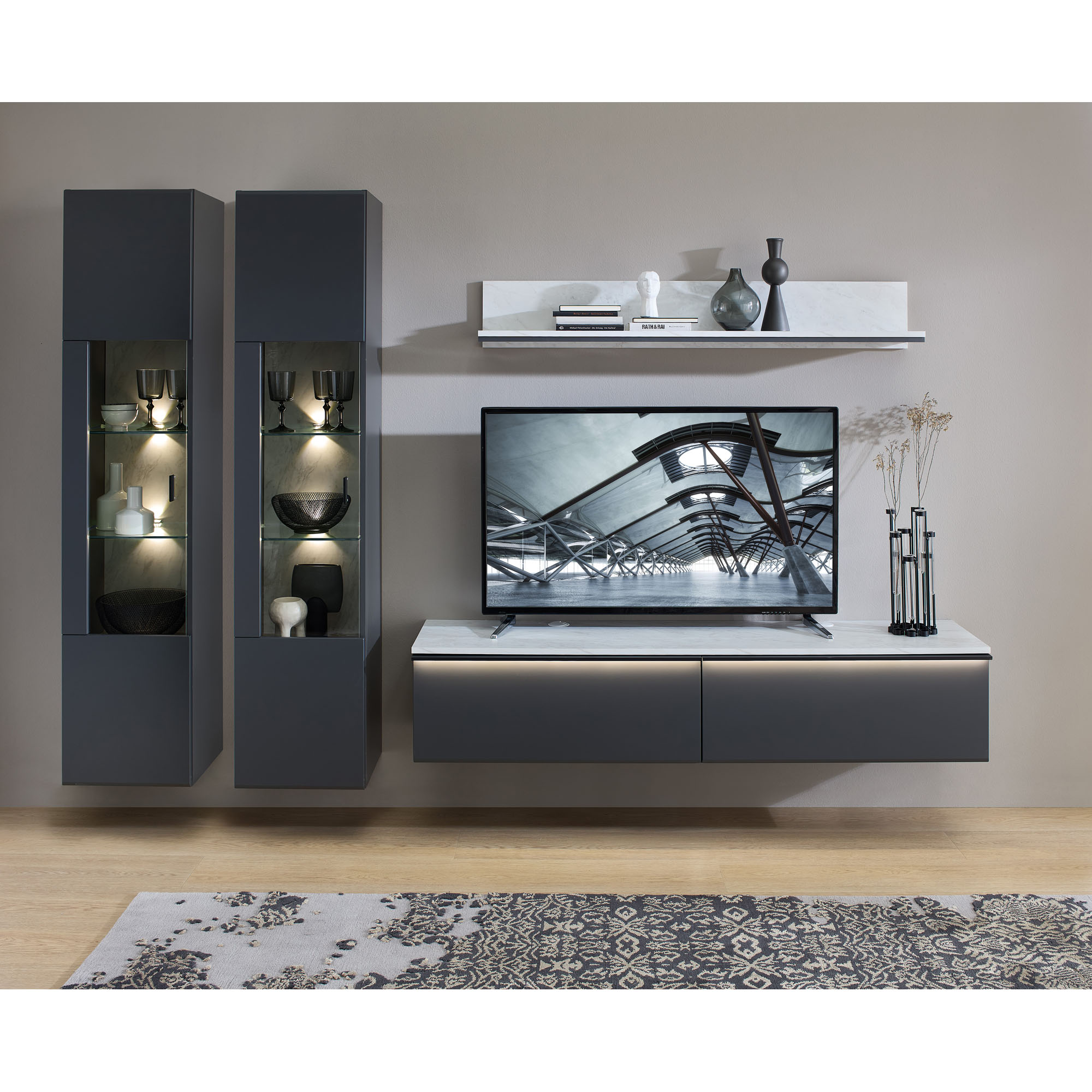 Moderne Vitrine in Anthrazit mit LED-beleuchteten Glasfächern als Bestandteil einer eleganten Wohnzimmereinrichtung.