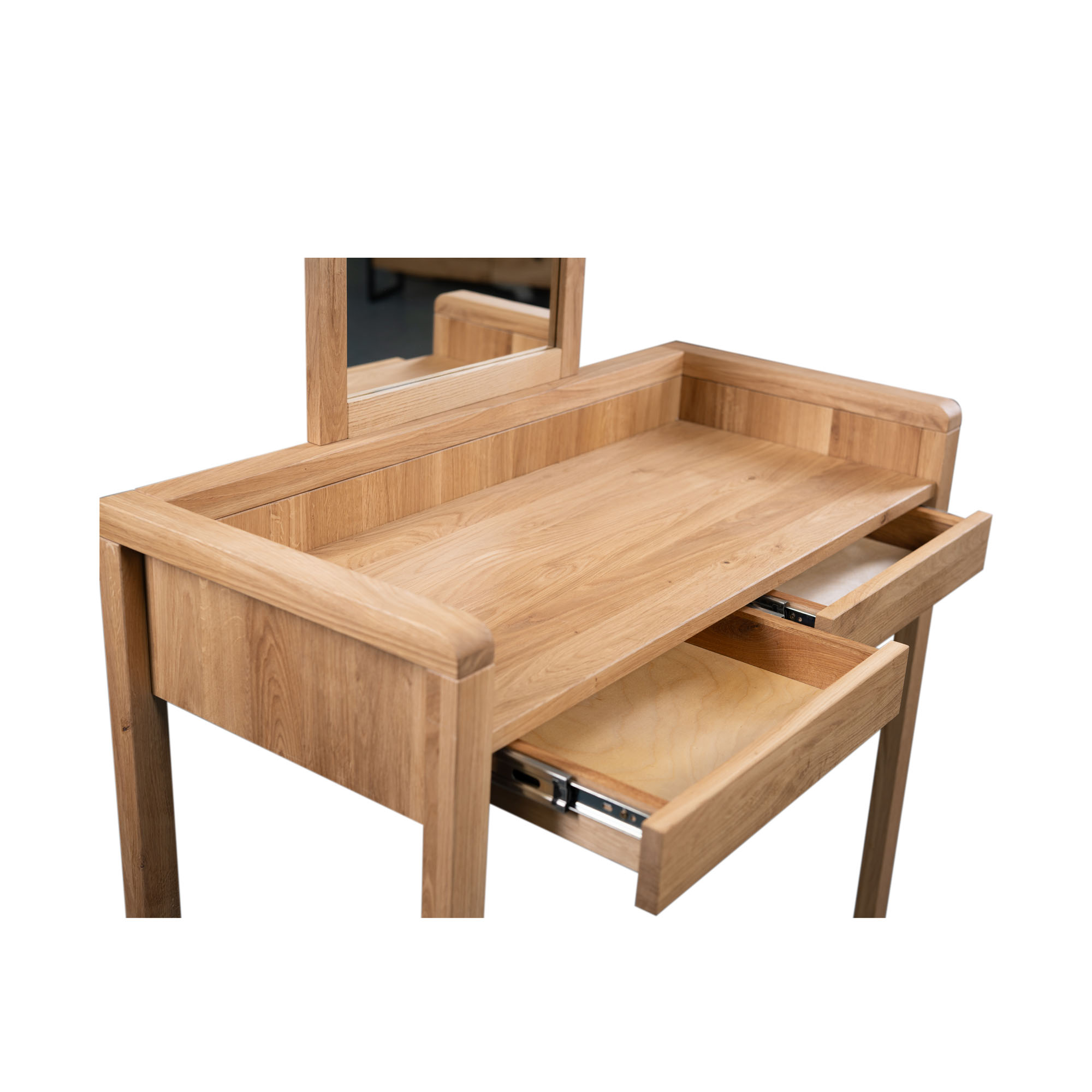 Nahaufnahme eines Schminktischs aus hellem Holz mit geöffneten Schubladen und Spiegel im Hintergrund