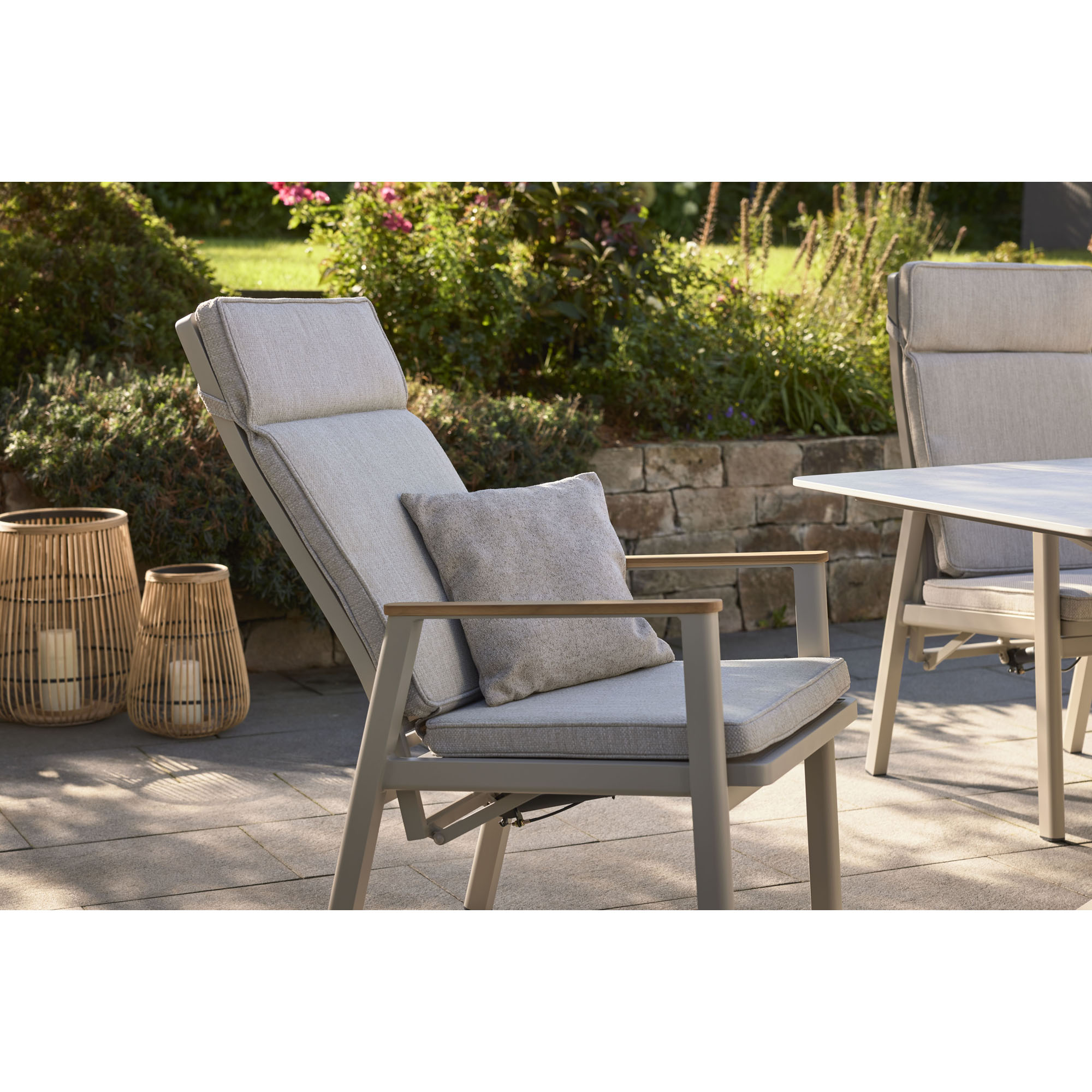 Gartenstuhl mit Polster auf einer Terrasse vor bepflanztem Gartenbereich
