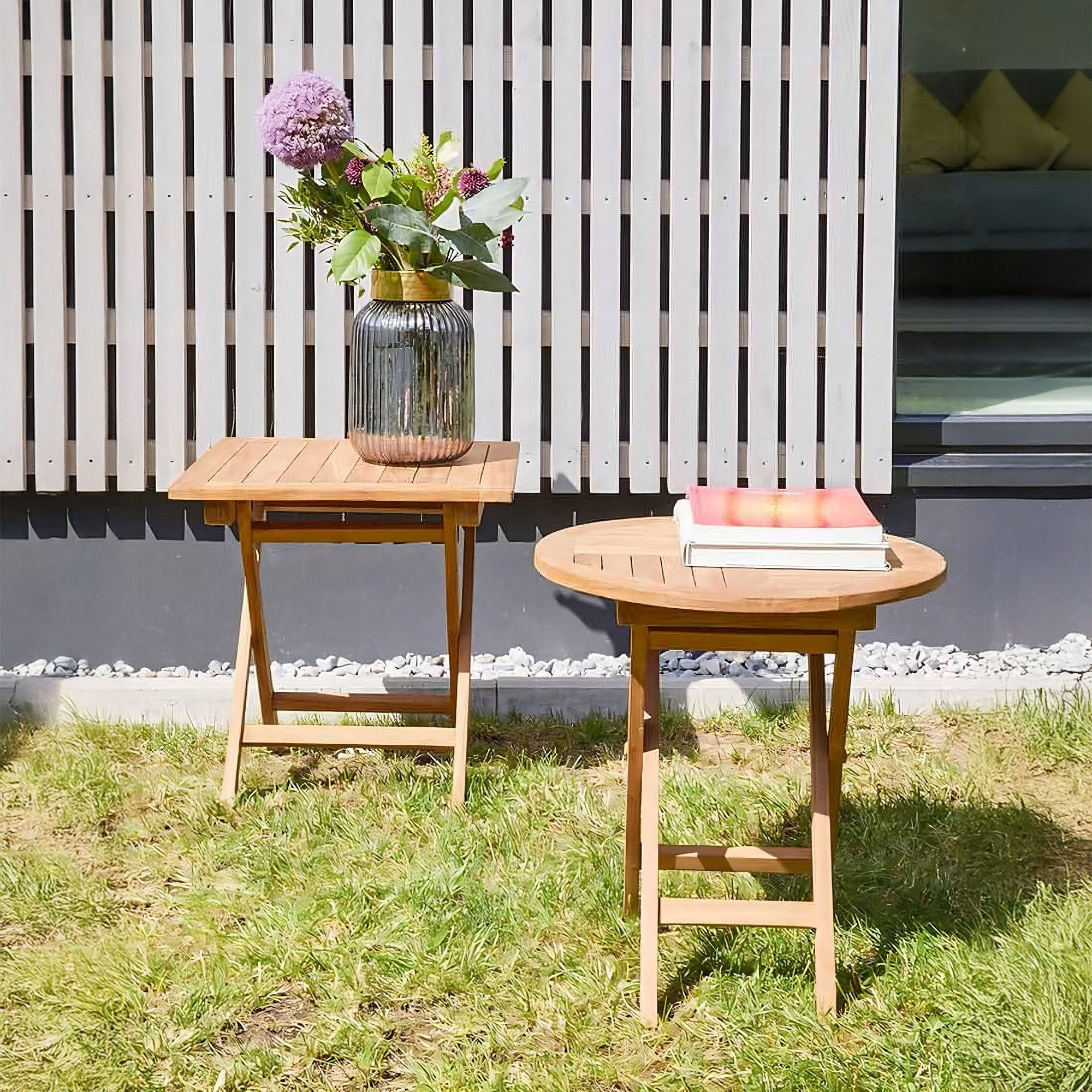 runder Klapptisch aus Holz im Außenbereich auf einer Rasenfläche neben einem weiteren Tisch
