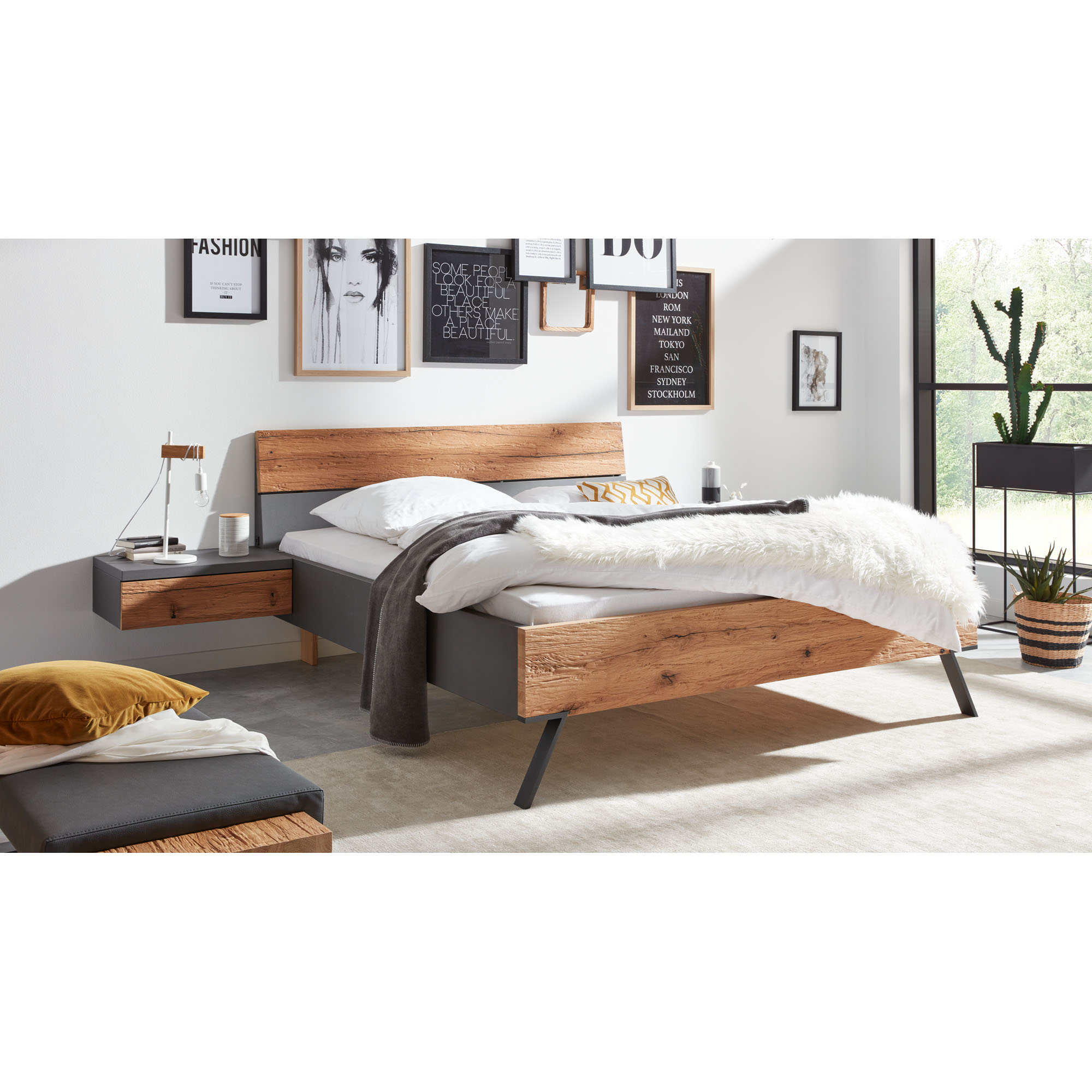 Interliving 1025 Doppelbett mit Holzoptik und grauem Rahmen in einem modern eingerichteten Schlafzimmer mit Nachttisch und Wandbildern