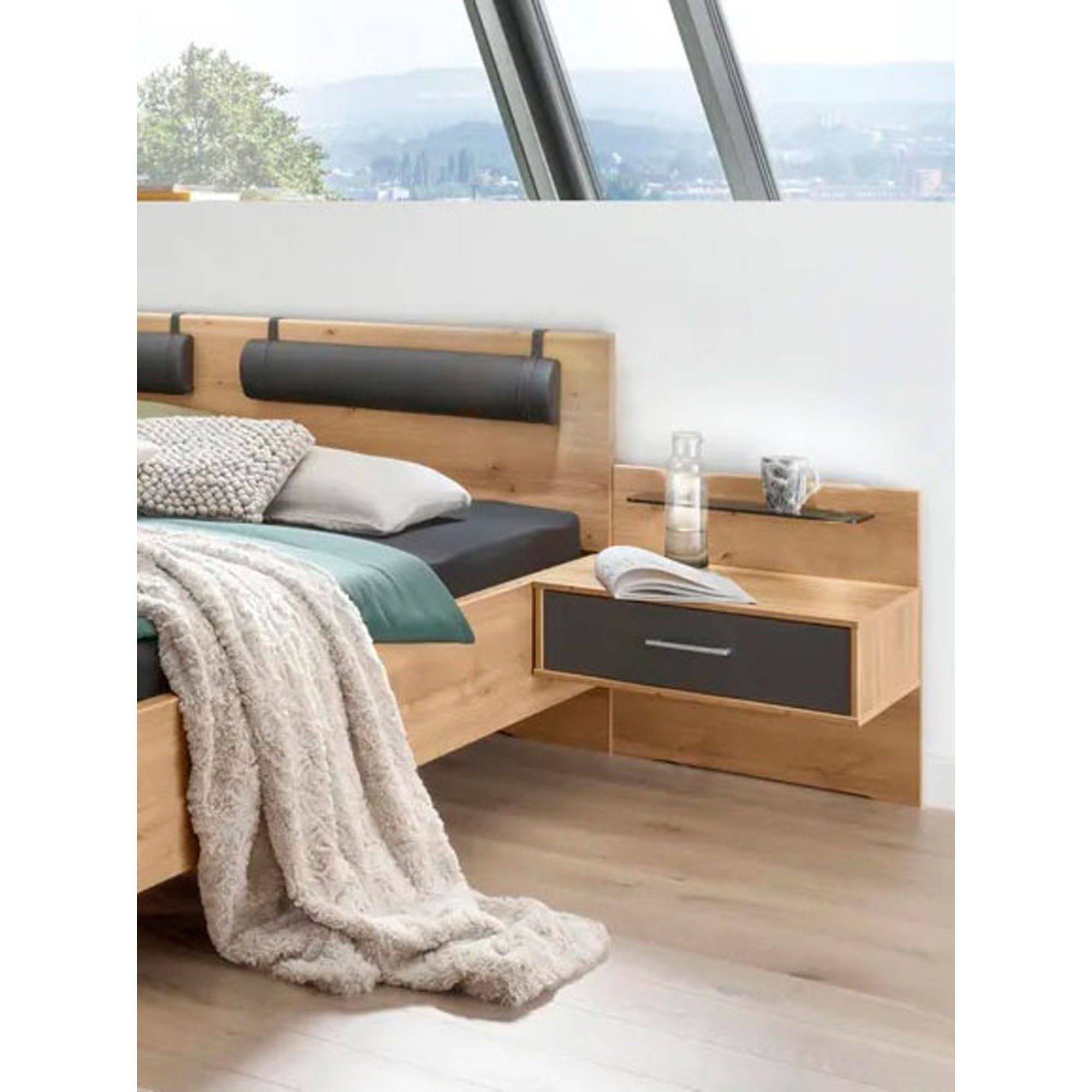 Helles Schlafzimmer mit Doppelbett in Holzoptik, schwebendem Nachttisch und großem Kleiderschrank mit dunklen Fronten unter Dachfenstern