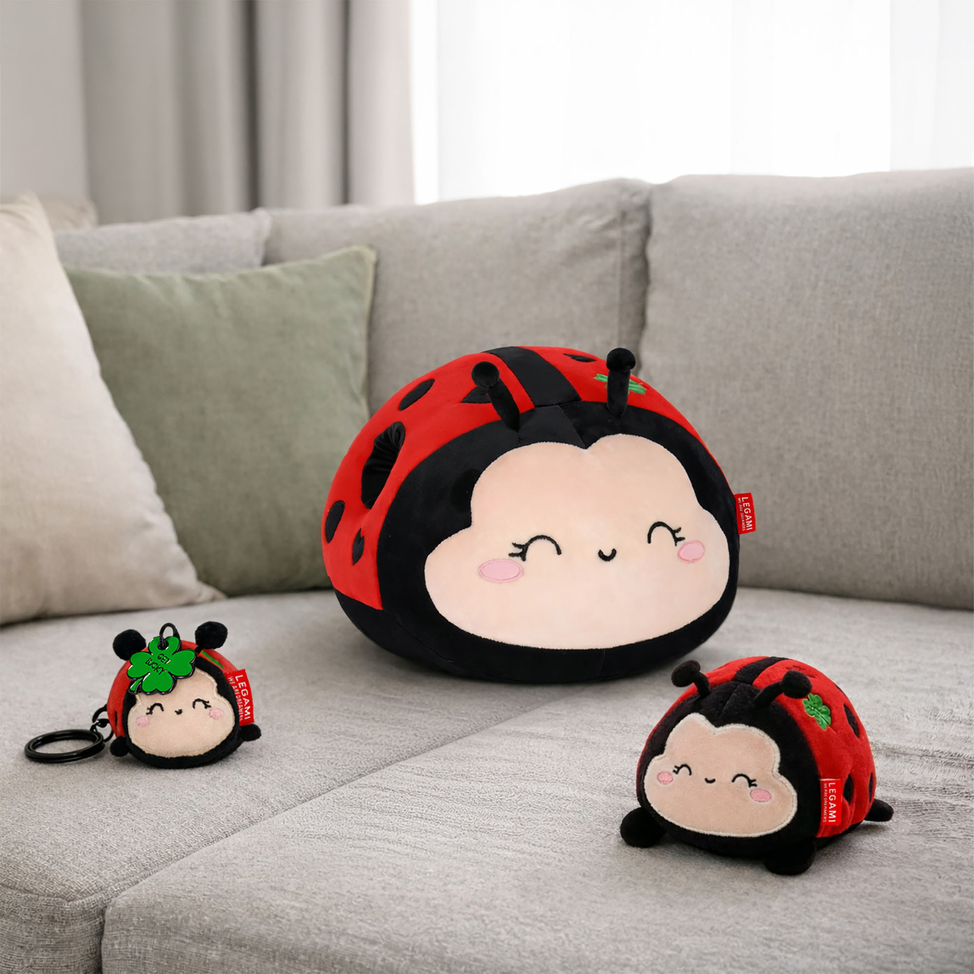 Marienkäfer-Plüschtier, auf einem Sofa zusammen mit einem kleineren passenden Marienkäfer-Anhänger dargestellt.