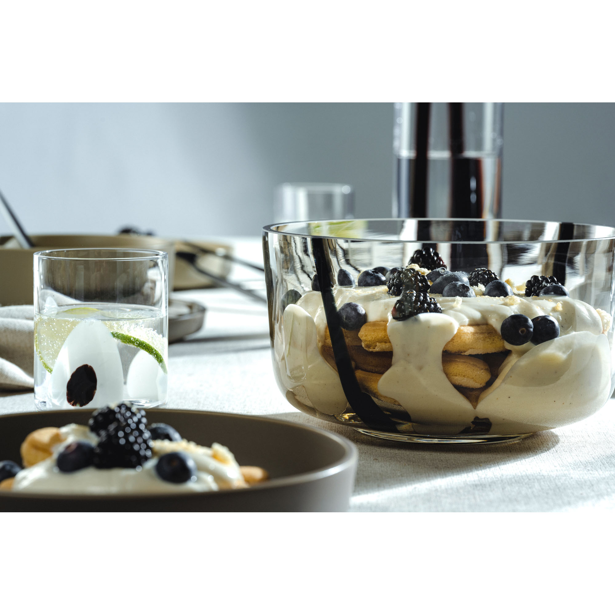Glasschale gefüllt mit Dessert und Beeren auf gedecktem Tisch