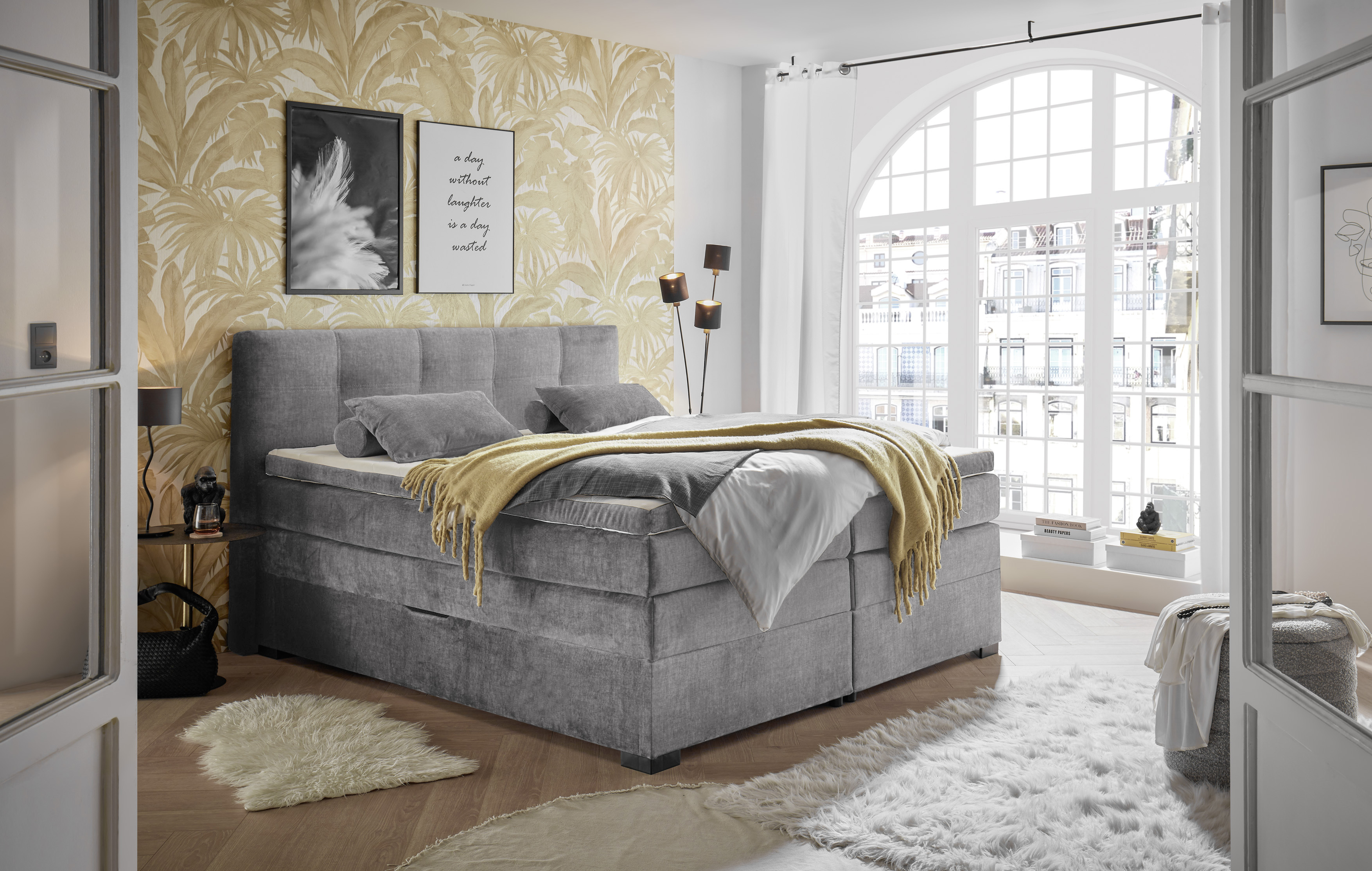 Boxspringbett „Vogue 15 grey“ in einem eingeriBchteten Schlafzimmer, dekoriert mit Kissen und Bettdecke, wohnliches Ambiente