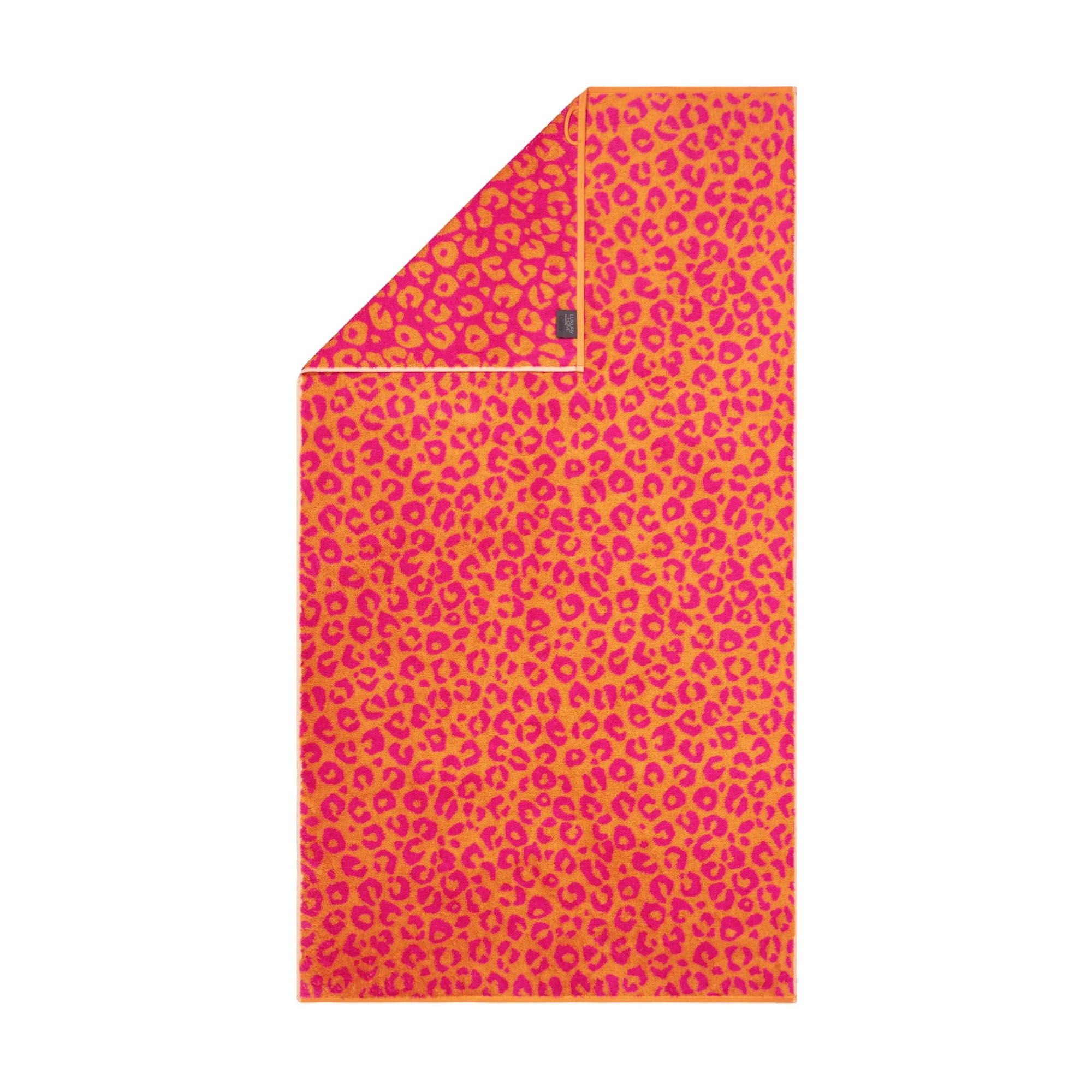 Duschtuch in der Farbe Pink mit Leopardenmuster in kräftigem Pink und Orange und umgeschlagener Ecke; Vorderseite, Rückseite und kleines Textiletikett sind sichtbar.