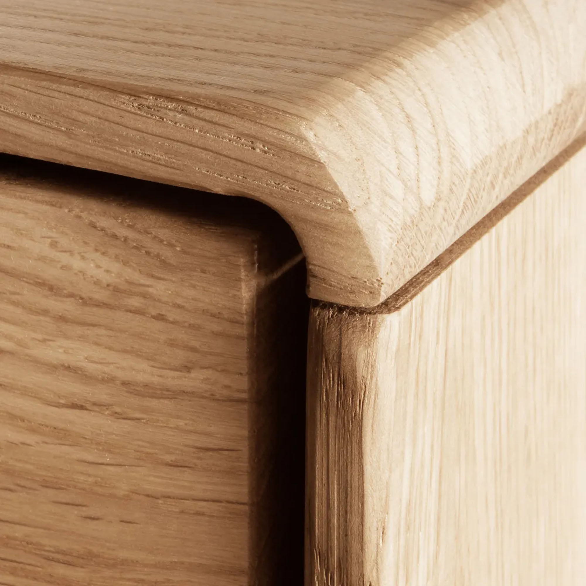 Nahaufnahme einer abgerundeten Ecke an einem Sideboard aus Holz mit sichtbarer Holzmaserung