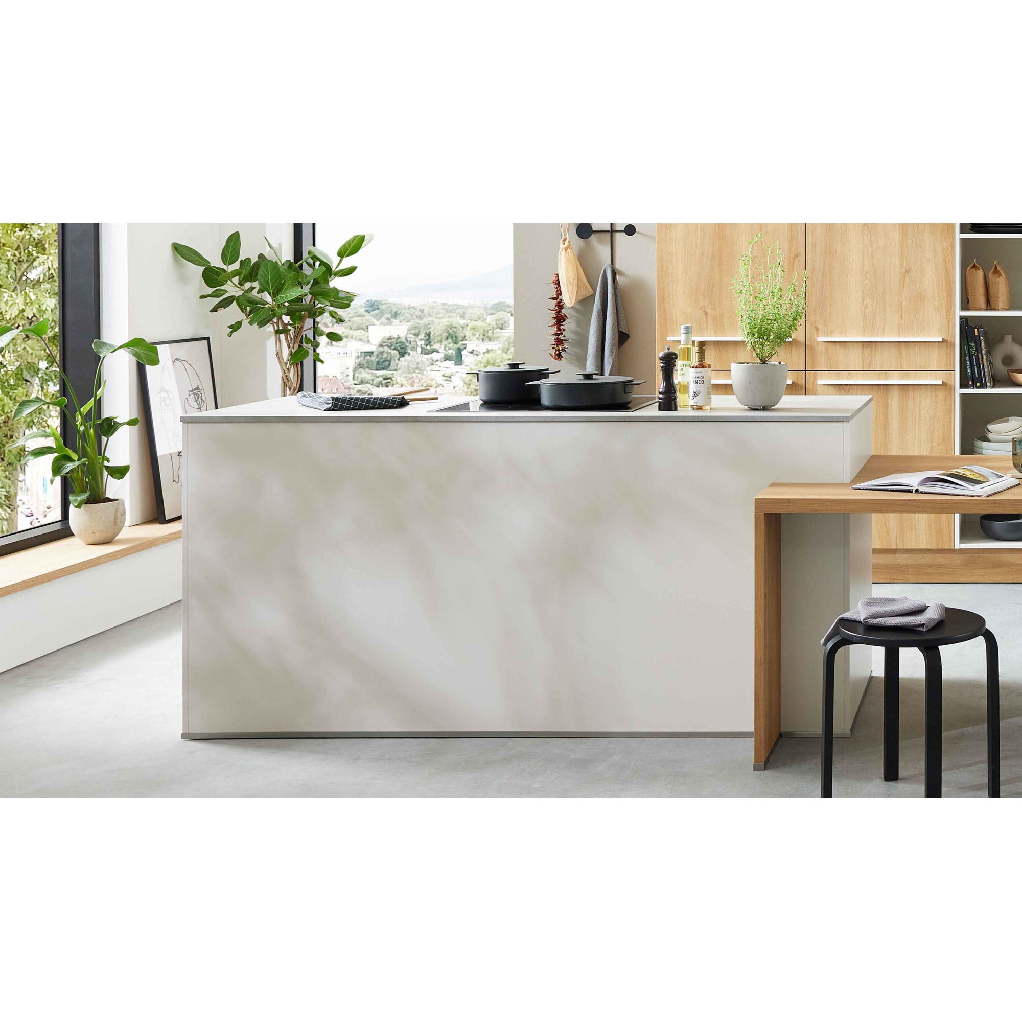 Kücheninsel mit Kochfeld, grünen Pflanzen und Holzdetails in heller moderner Raumgestaltung