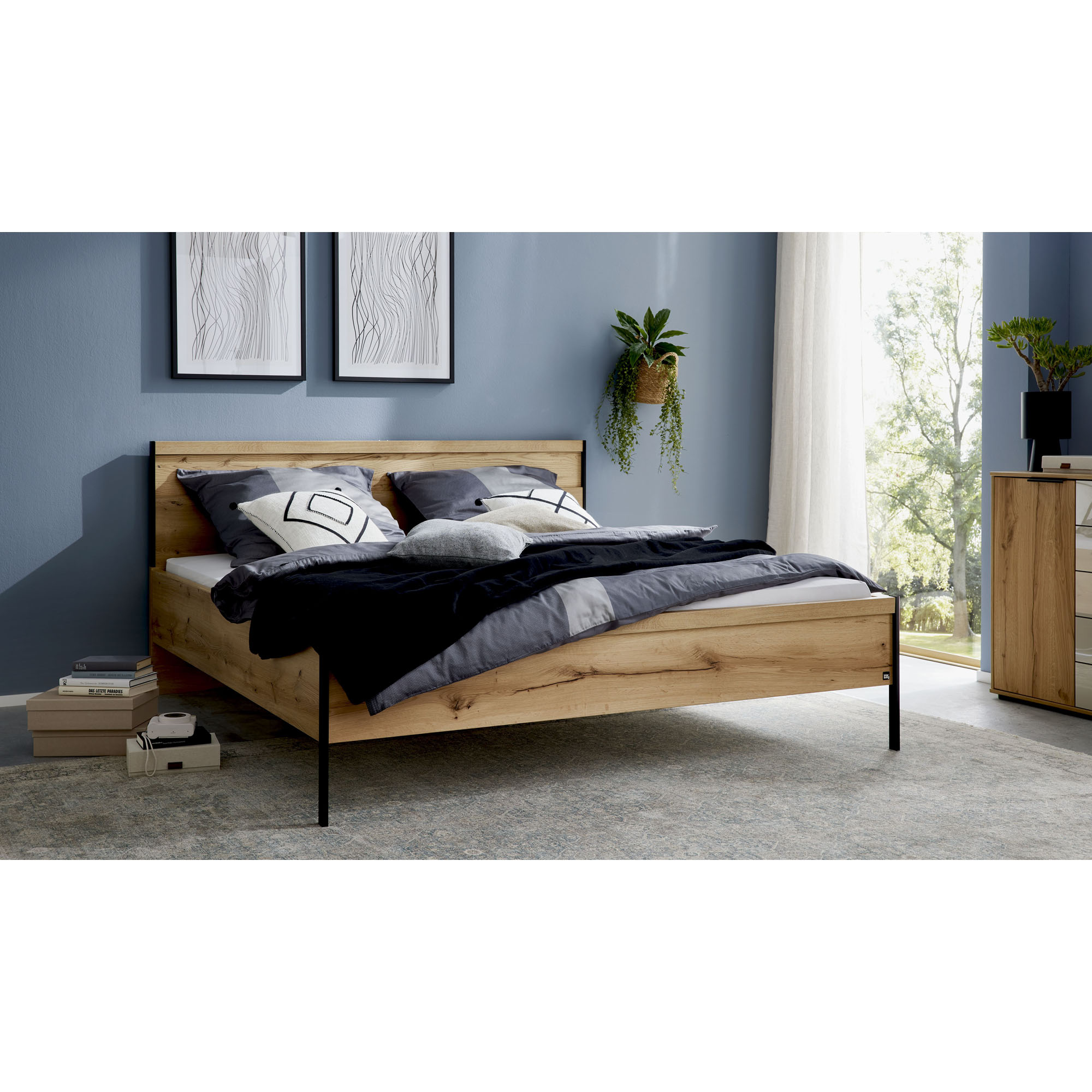 Interliving 1034 Bett in Holzoptik mit schwarzem Metallrahmen in einem modern eingerichteten Schlafzimmer