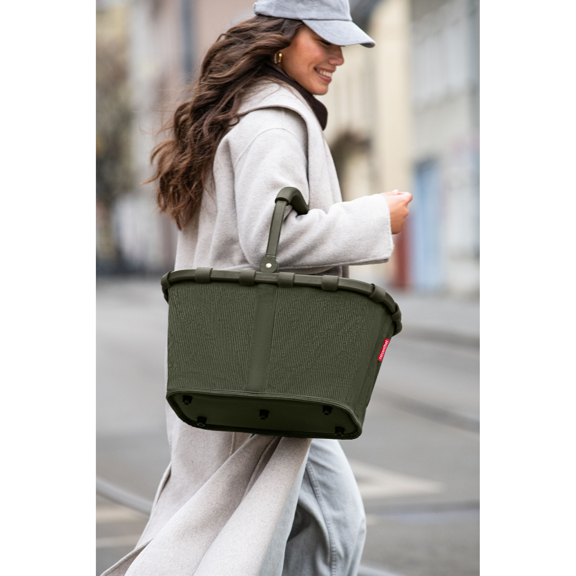 Einkaufskorb von Reisenthel, Modell Carrybag, in Dunkelgrün aus geripptem Cord, von einer Person am Griff getragen.