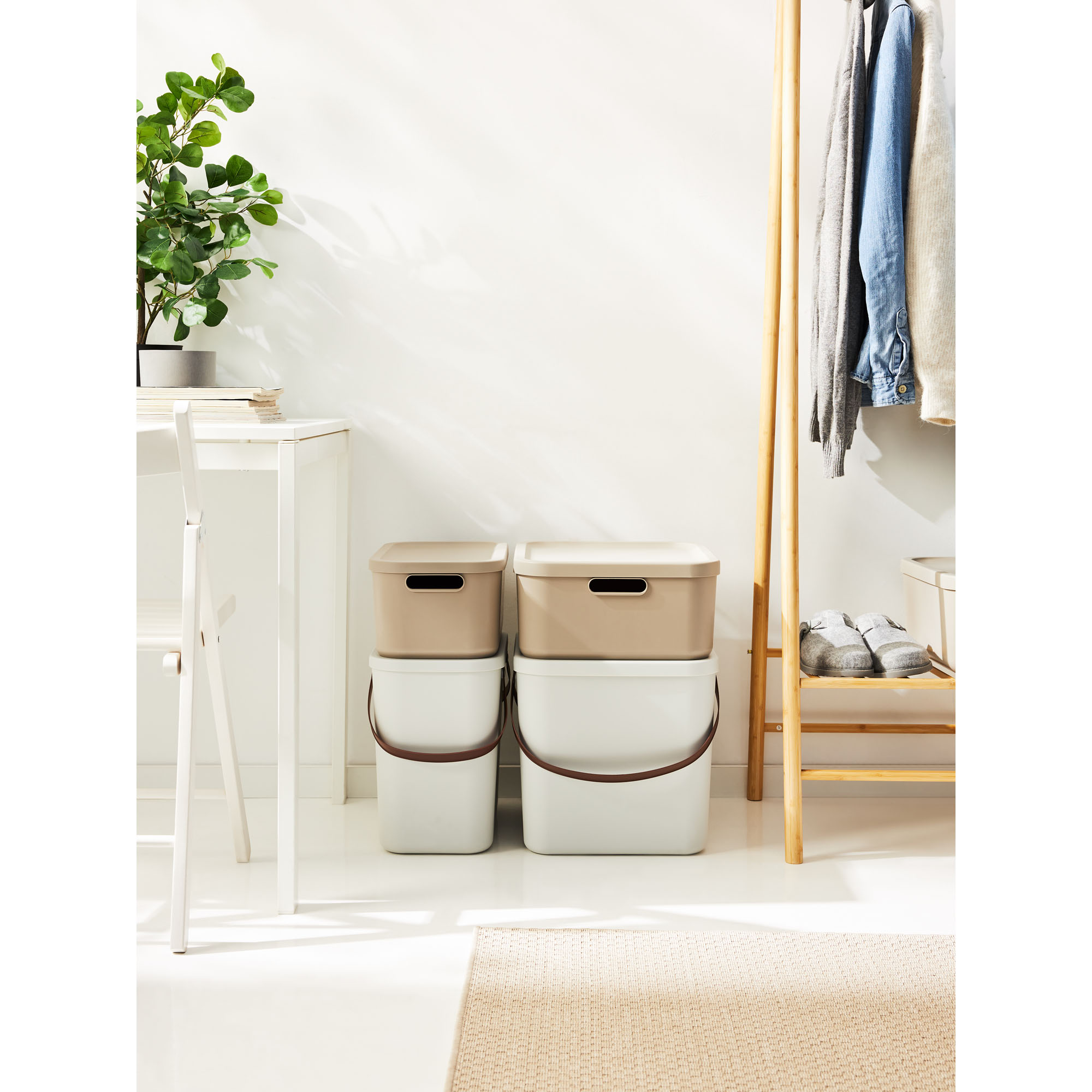 Beige Aufbewahrungsboxen mit Deckeln auf dem Boden neben einer Garderobe im Eingangsbereich