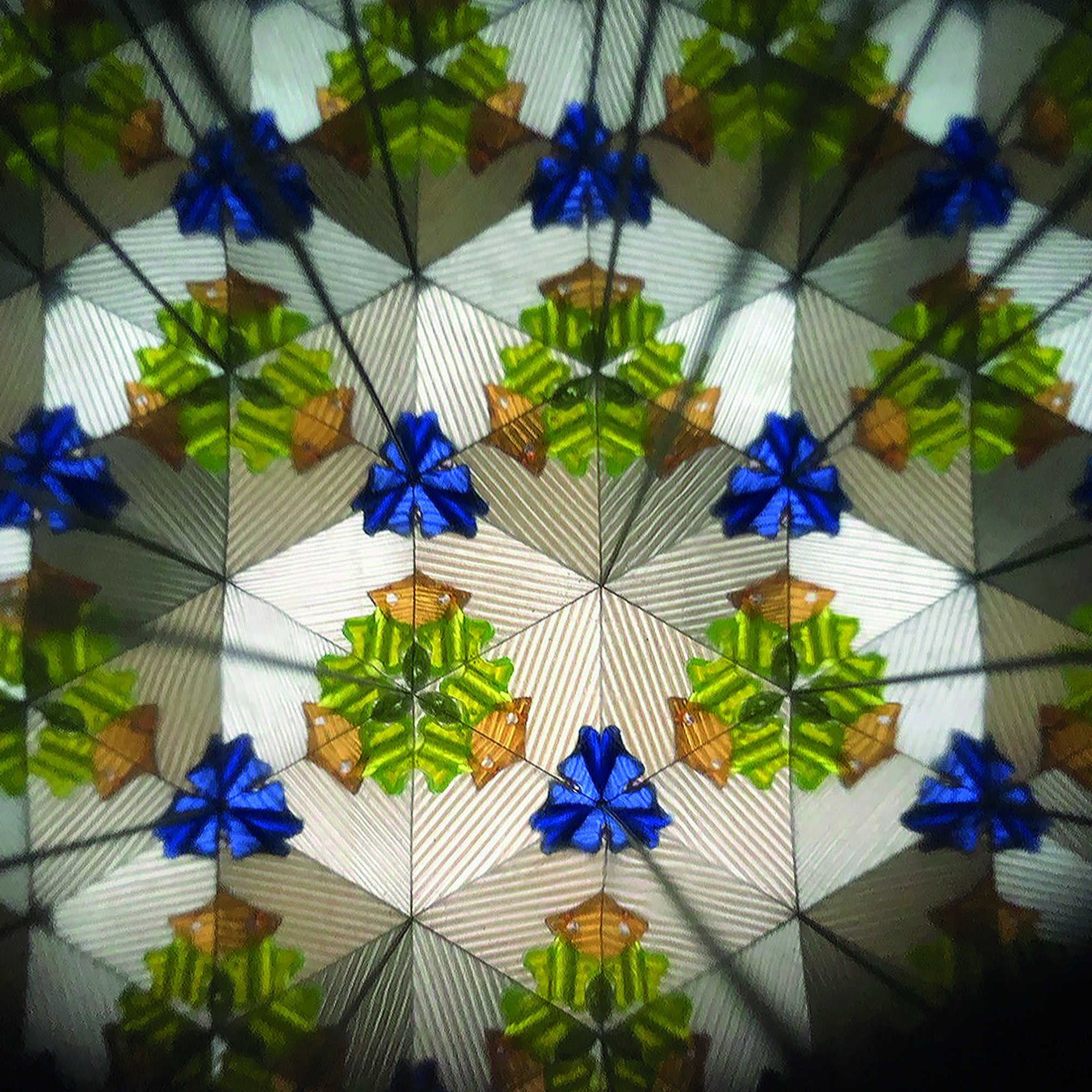 Blaues Kaleidoskop mit Weltraummotiv, mit einem zweiten symmetrischen Muster aus farbigen Figuren gezeigt.