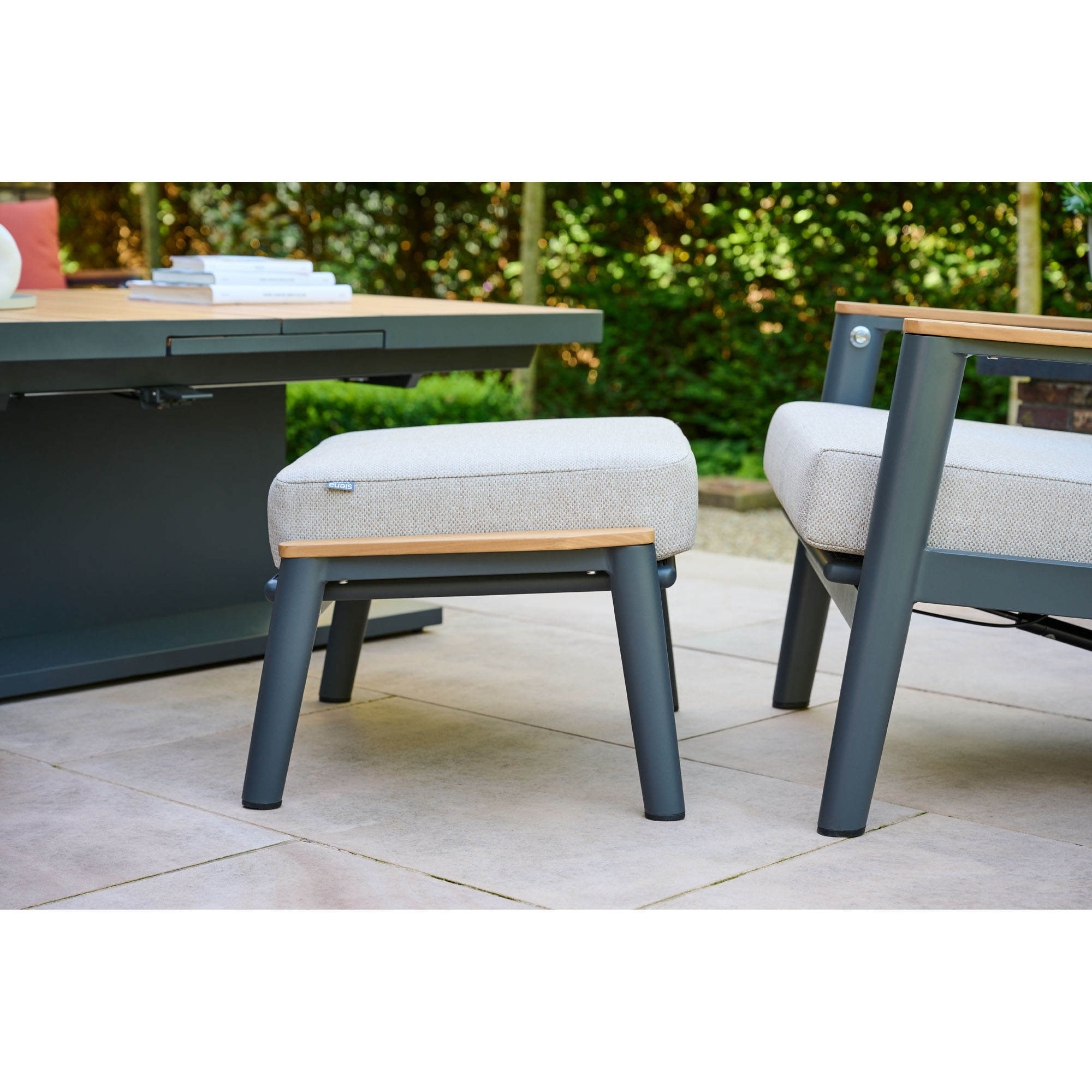 Beigefarbener Gartenhocker auf einer Terrasse, kombiniert mit passendem Sessel und Gartentisch in moderner Umgebung.