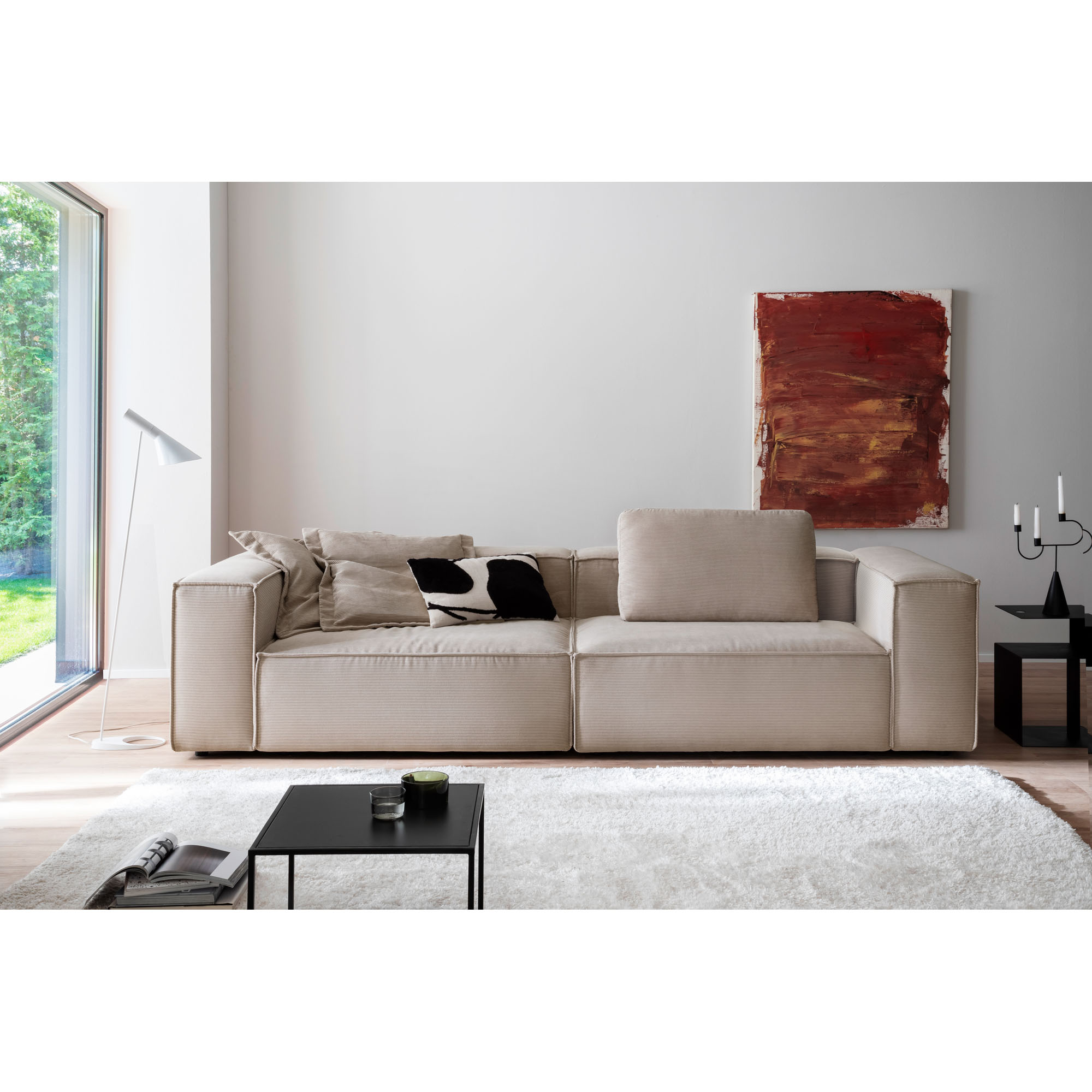 Sofa in einem modernen Wohnzimmer mit Teppich Couchtisch Stehleuchte und Wandbild