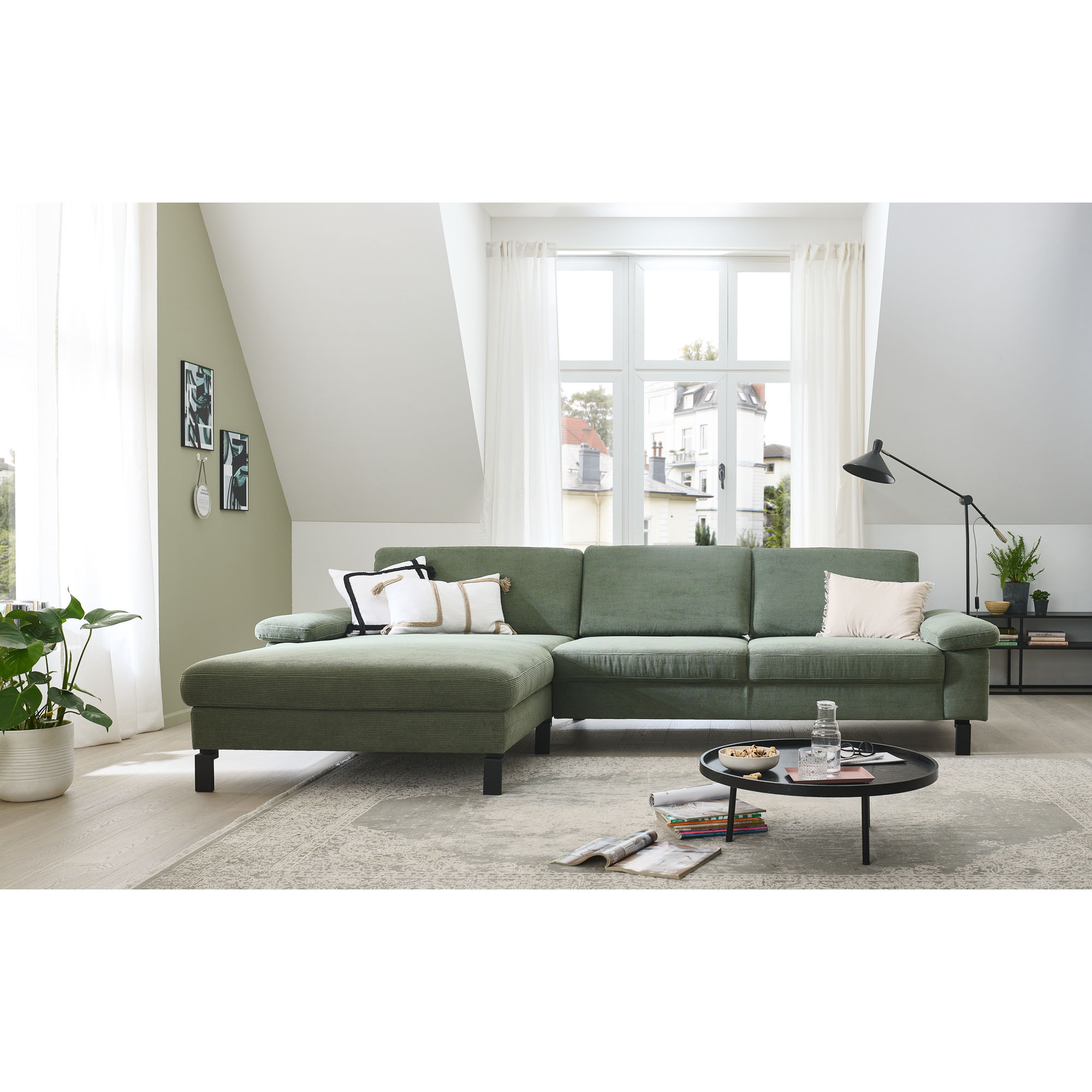 Ecksofa mit rechter Ottomane in einem hellen Wohnraum mit Teppich und Couchtisch