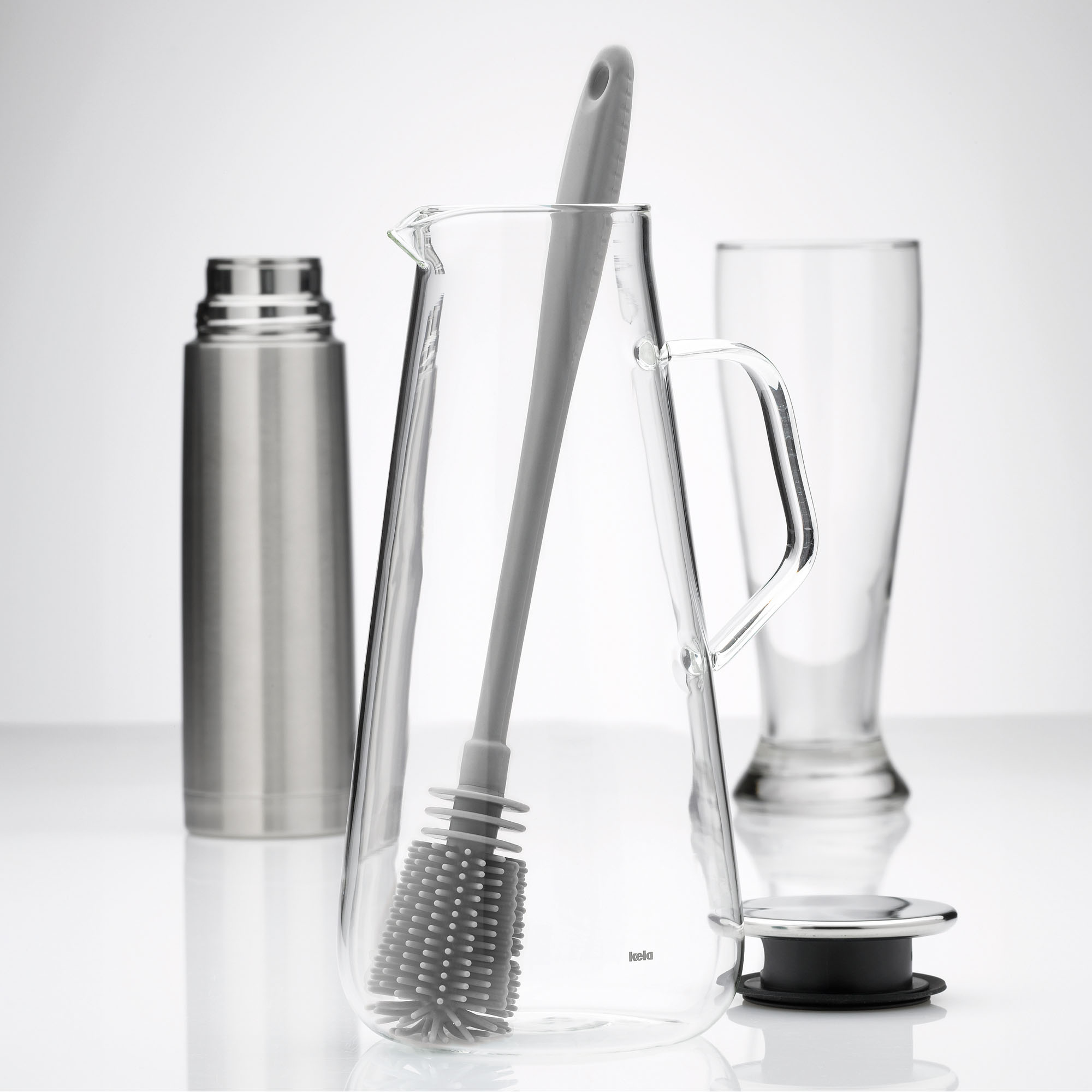 Lichtgraue Flaschenbürste auf einer Arbeitsfläche neben Flasche und Gläsern