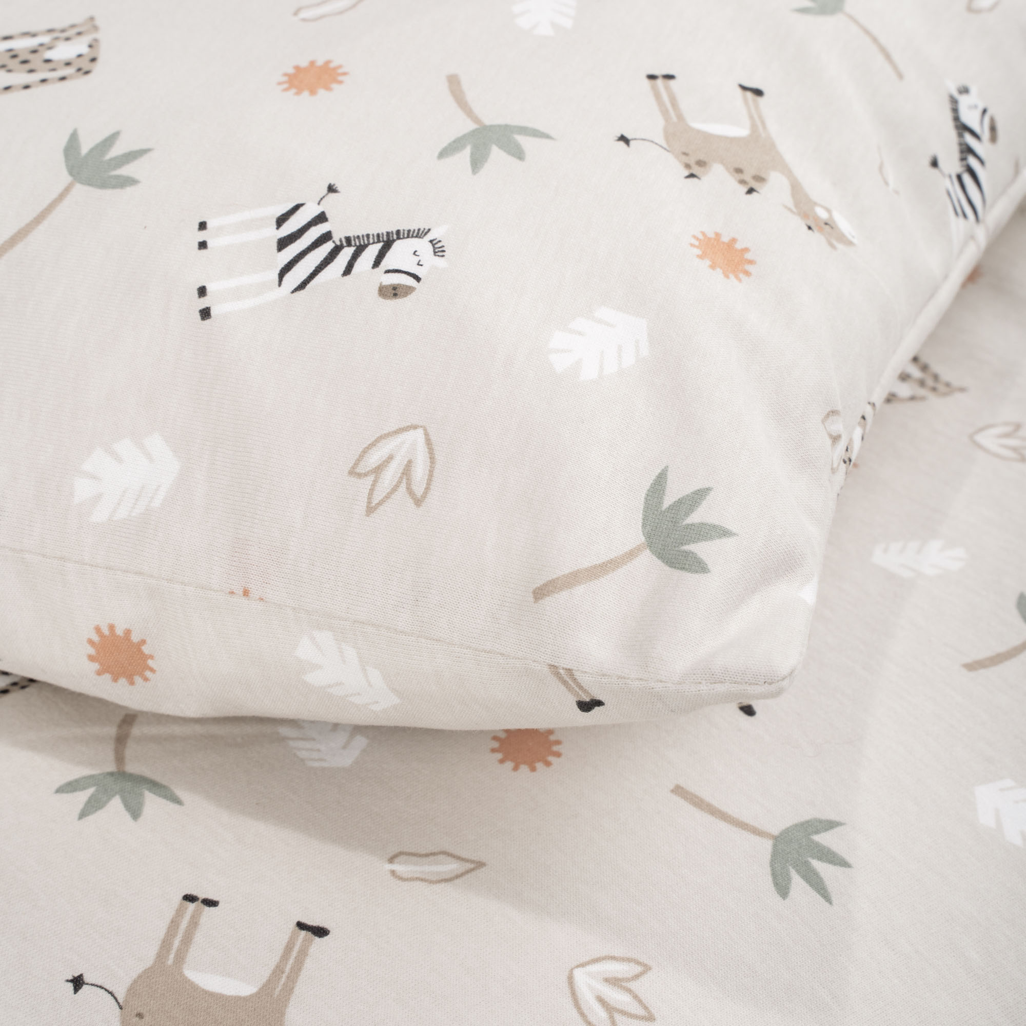 Nahaufnahme der Kinderbettwäsche mit Safari-Tieren, Blättern und Pflanzenmotiven in Beige und dezenten Farben