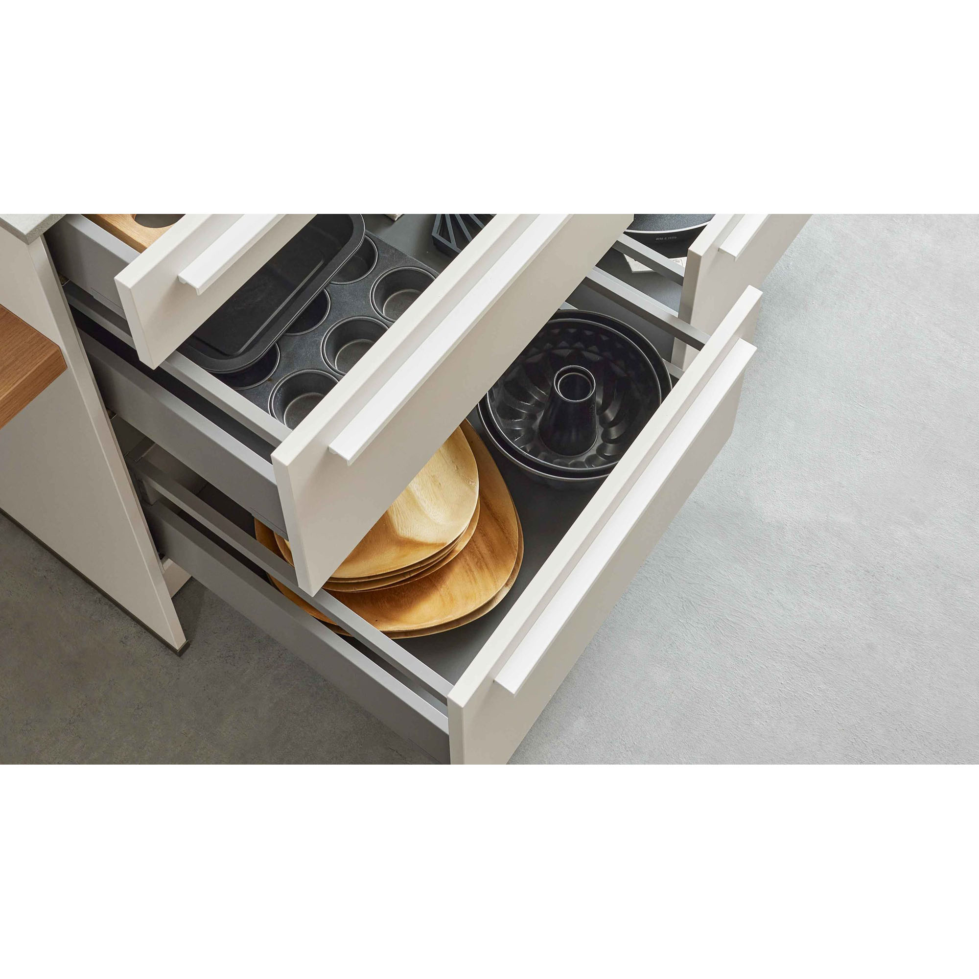 Küchenschubladen mit Backformen, Holzschalen und Backzubehör in heller Küchenzeile
