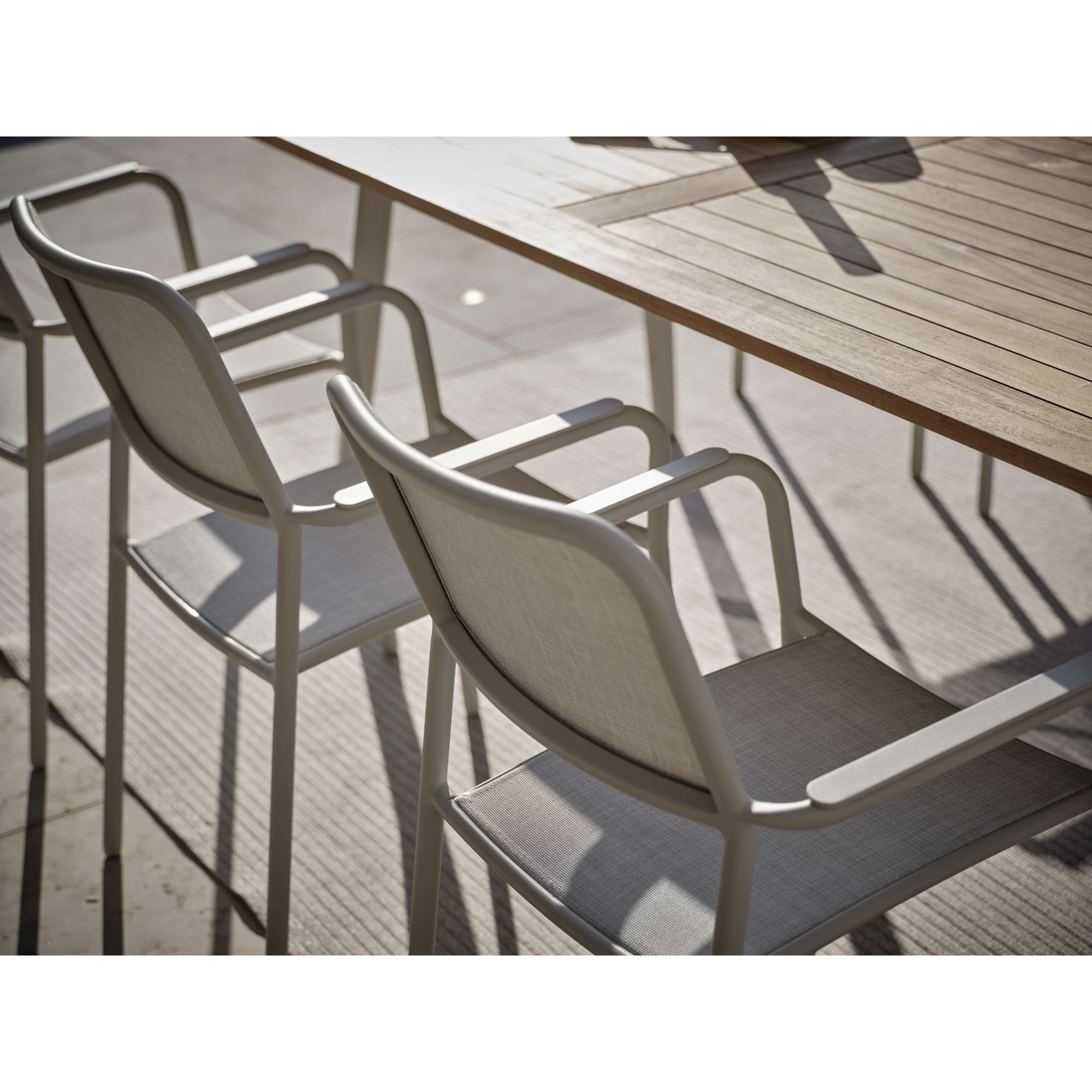 Zwei Gartenstühle mit Armlehnen an Tisch aus schräger Seitenansicht auf Terrasse