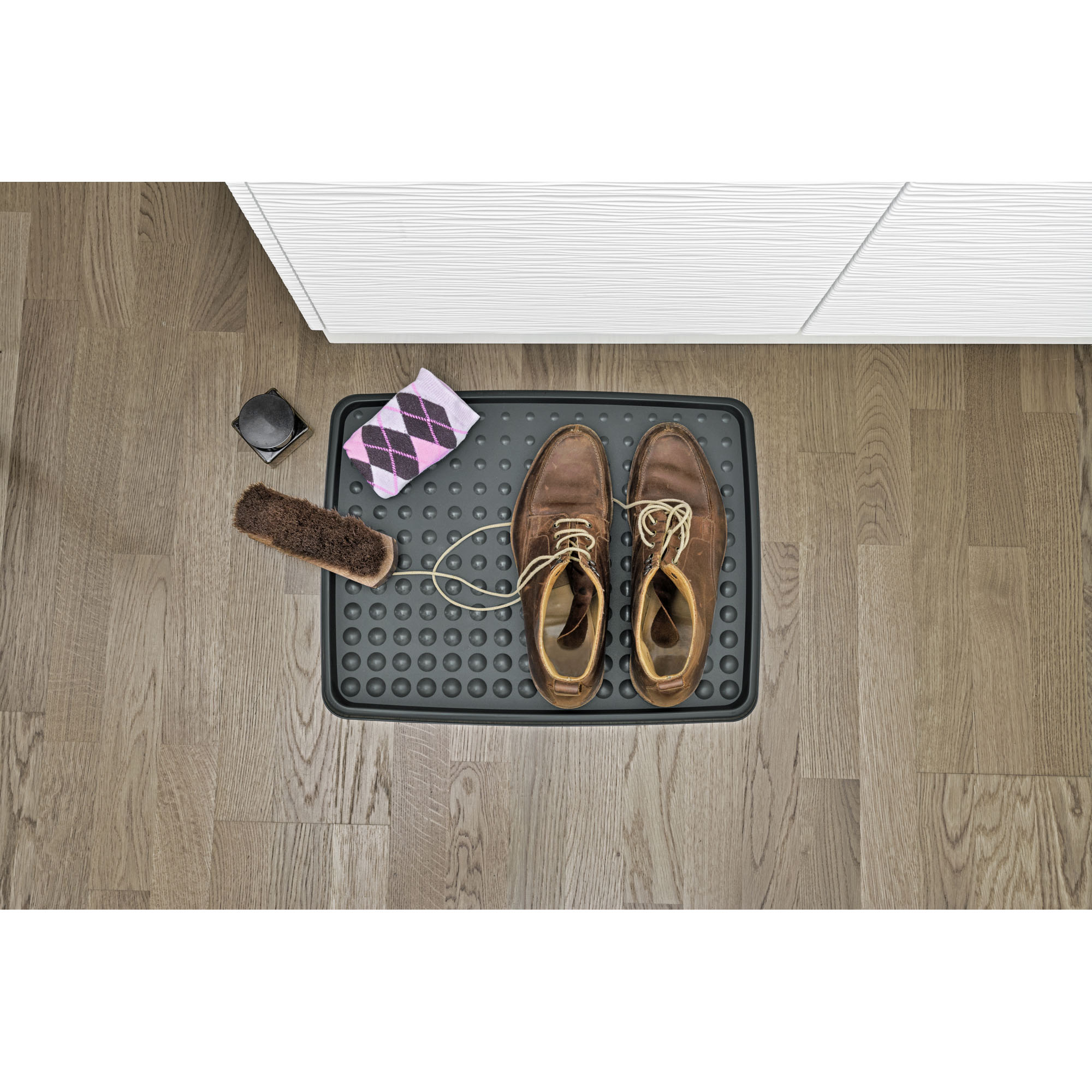 Schuhabtropfschale auf dem Boden mit einem Paar Schuhe und abgelegten Gegenständen darauf