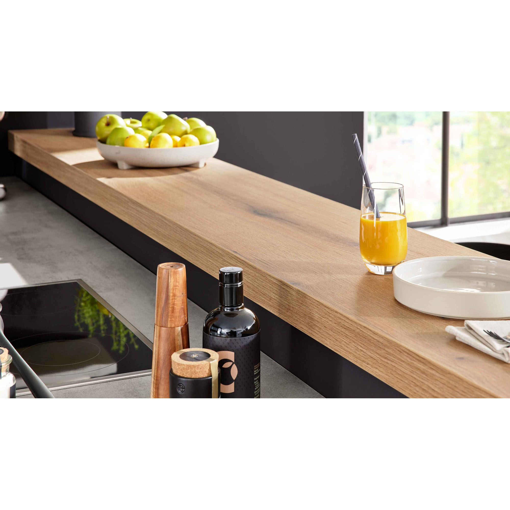 Küchenarbeitsplatte mit Holzaufsatz, Orangensaft, Obstschale und Gewürzmühlen in heller Küche