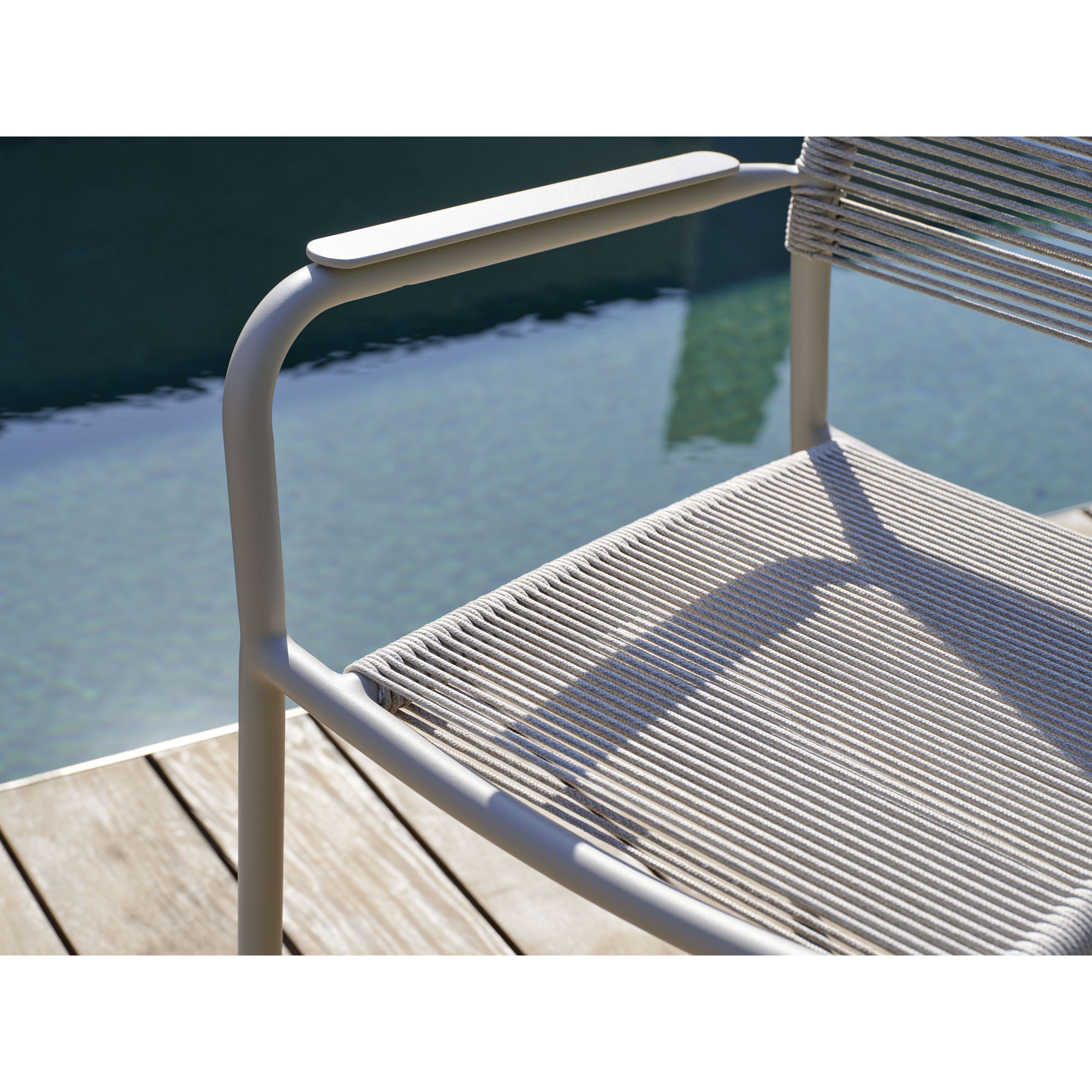 Nahaufnahme der Armlehne eines Gartenstuhls neben Wasserfläche