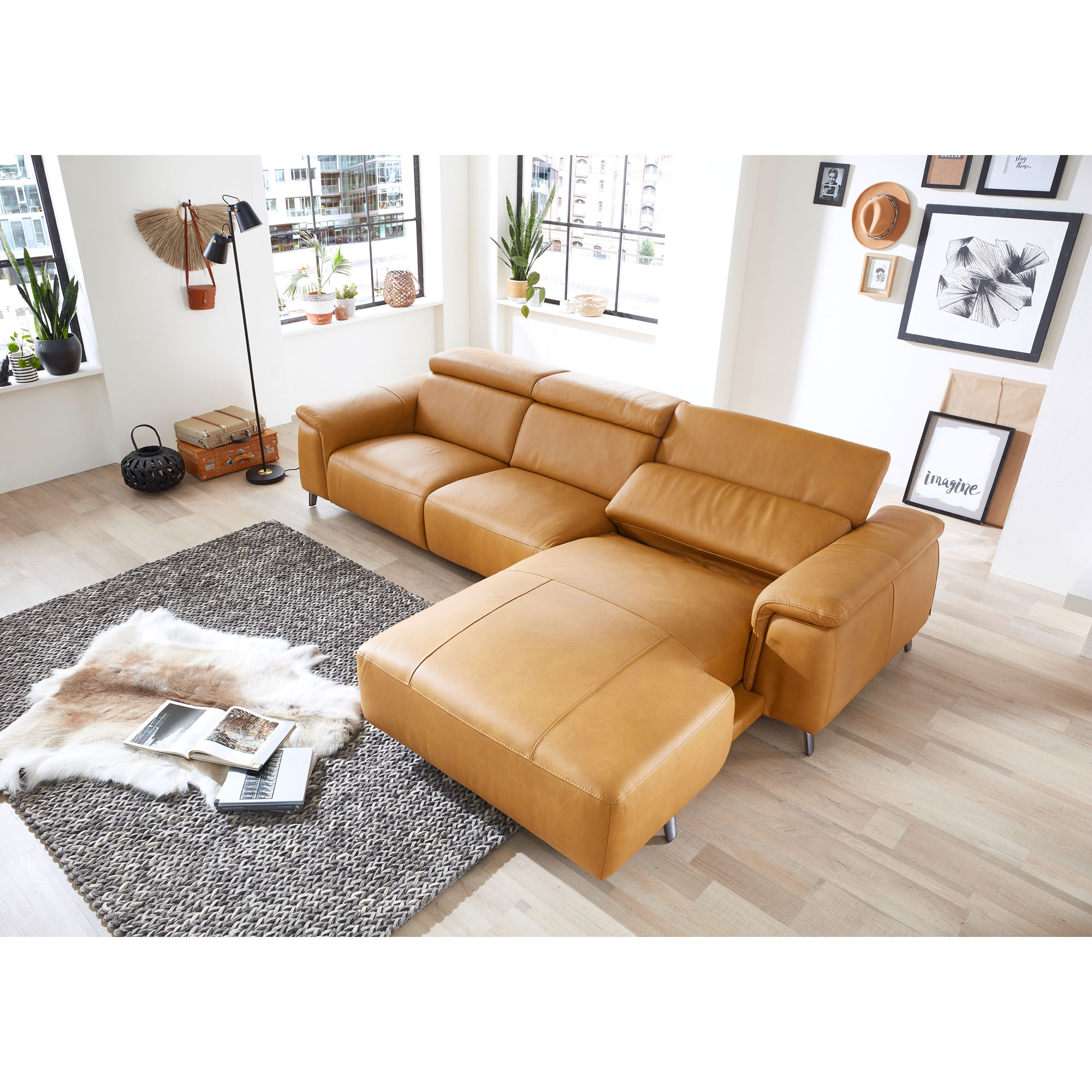 Cognacfarbenes Ecksofa mit Recamiere in einem hellen Wohnraum mit Teppich und Couchtisch