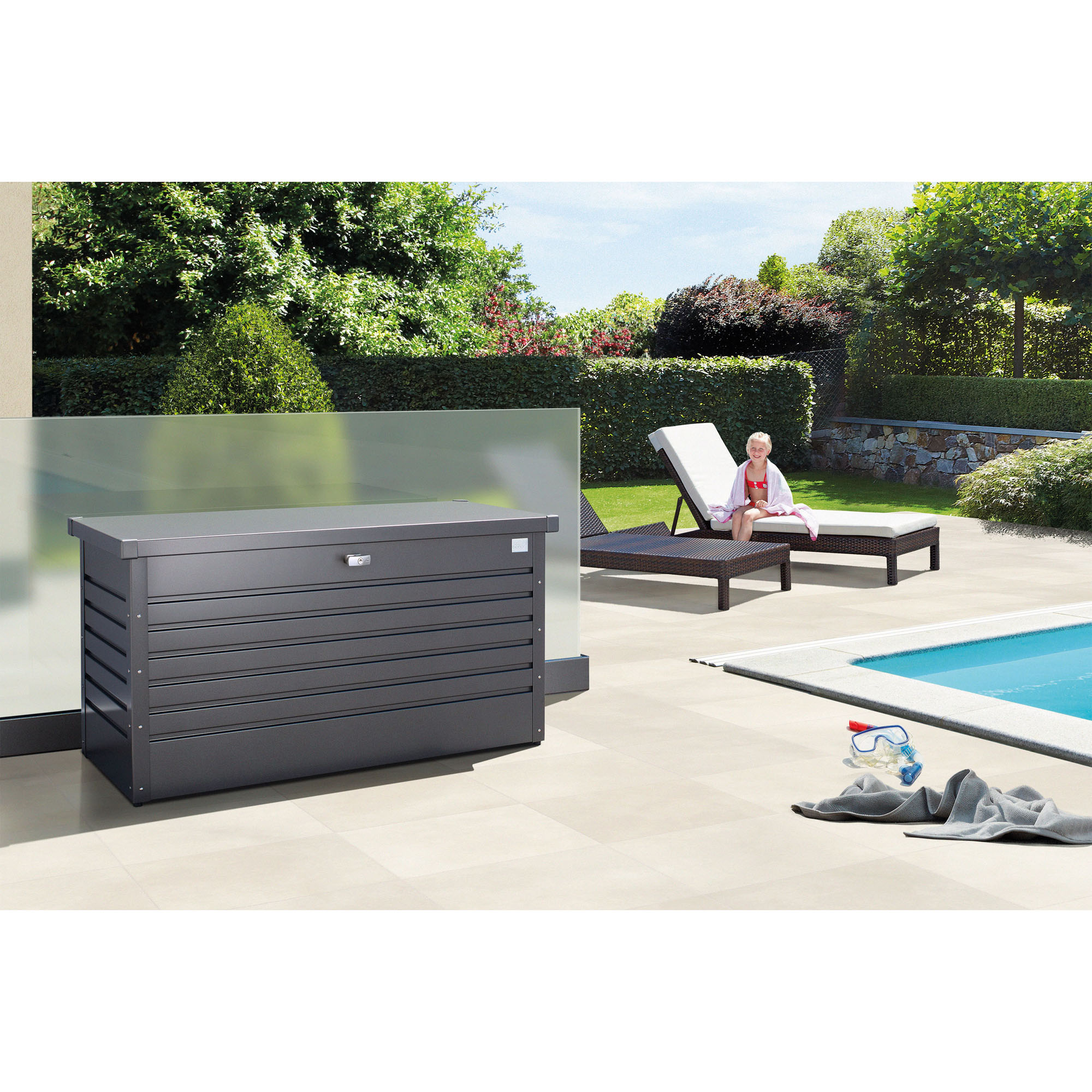 Graue Auflagenbox aus Metall auf einer Terrasse neben einem Pool im Garten
