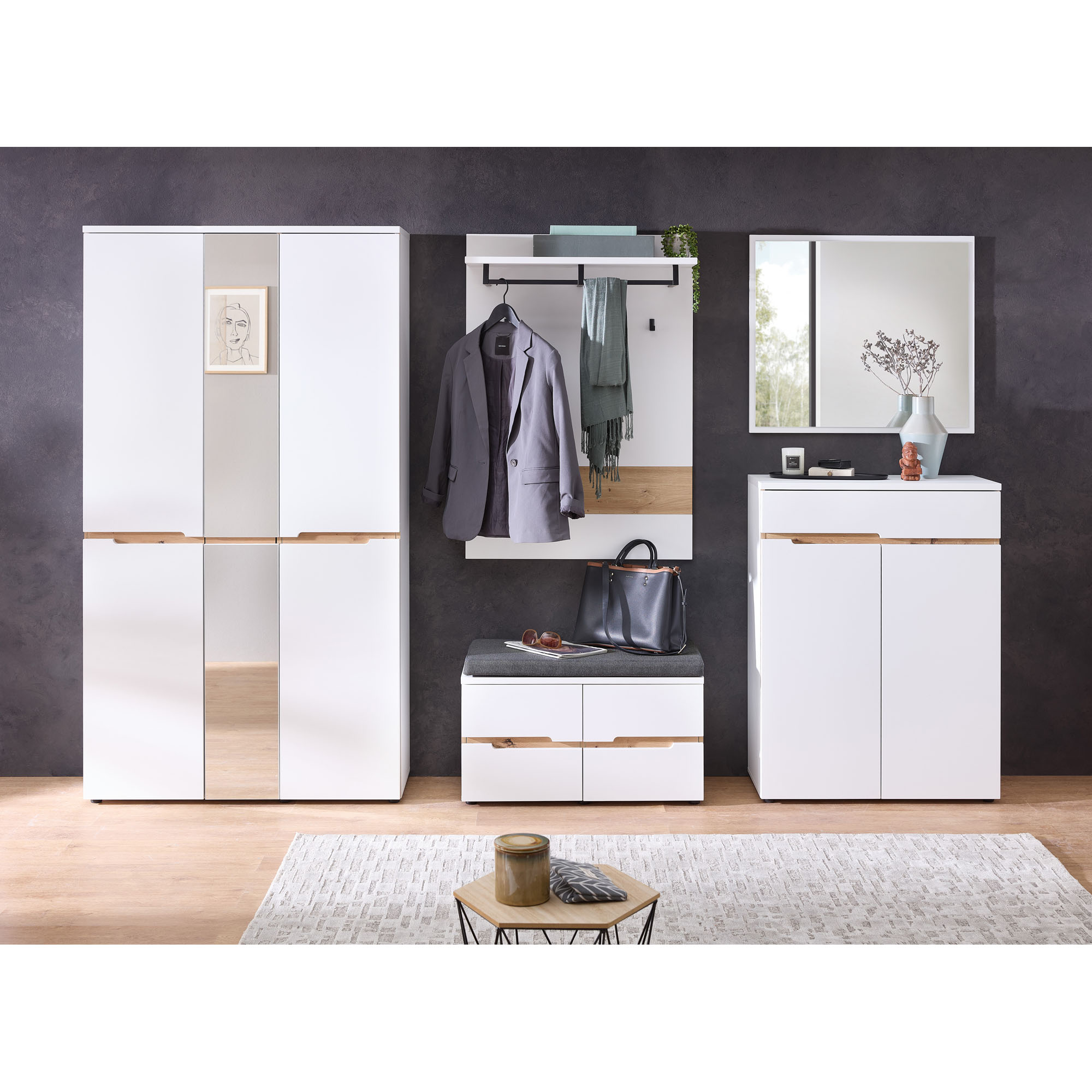 Eingestellter Garderobenbereich mit weißem Schrank, weißem Wandpaneel, Sitzbank und Kommode vor dunkler Wand, mit Kleidung und Accessoires dekoriert.