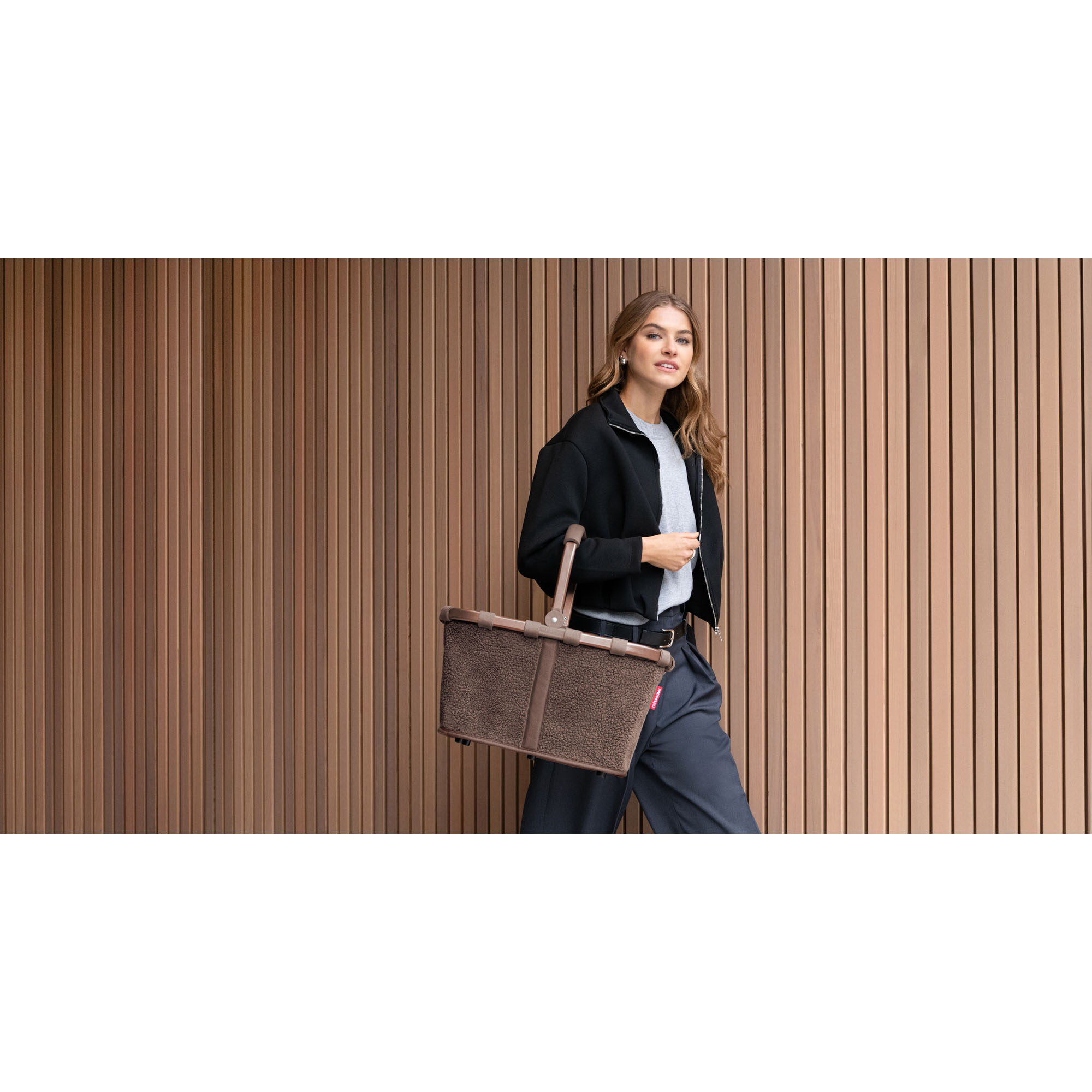 Einkaufskorb von Reisenthel, Modell Carrybag, in Schokoladenbraun aus Teddyfleece, von einer Person am Tragegriff getragen