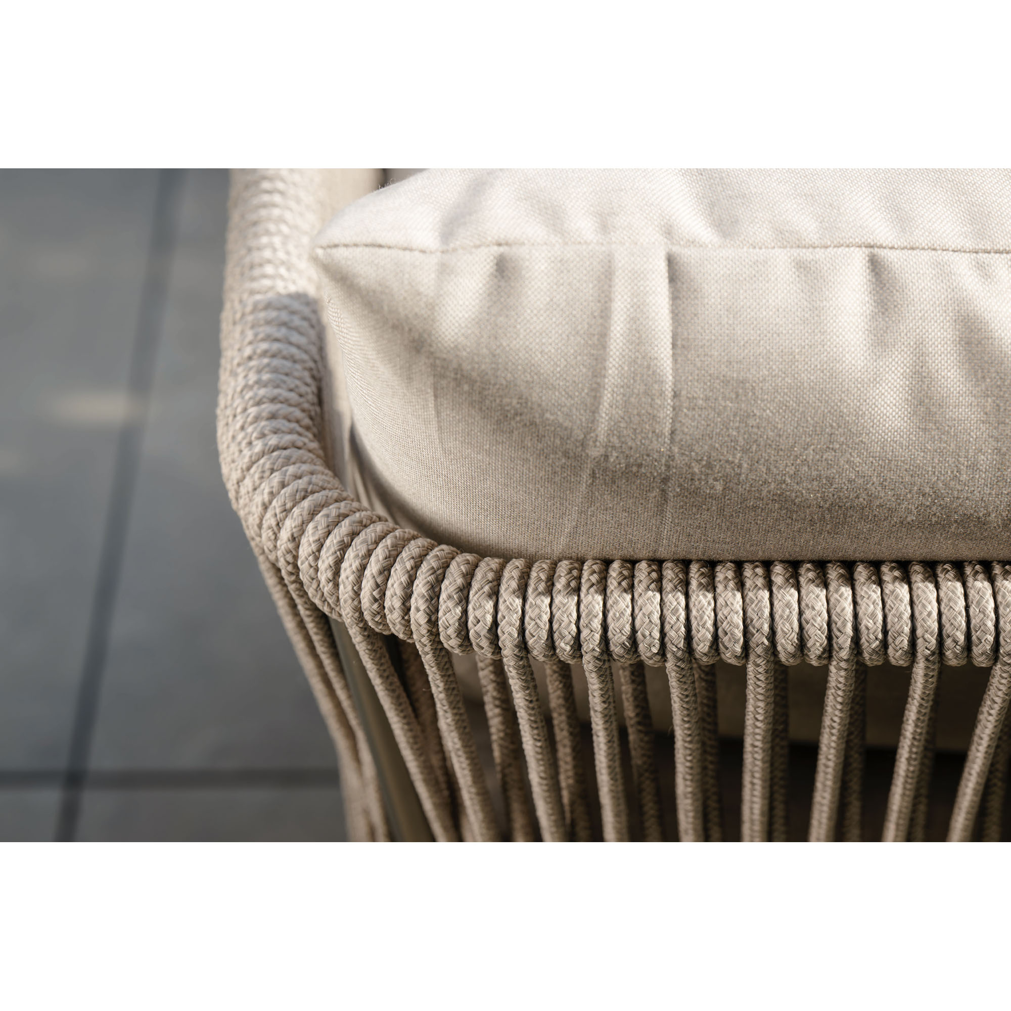 Nahaufnahme der Armlehne eines Sofas mit beigem Seilgeflecht und hellem Rückenkissen. Die Struktur des geflochtenen Seils ist deutlich zu erkennen.