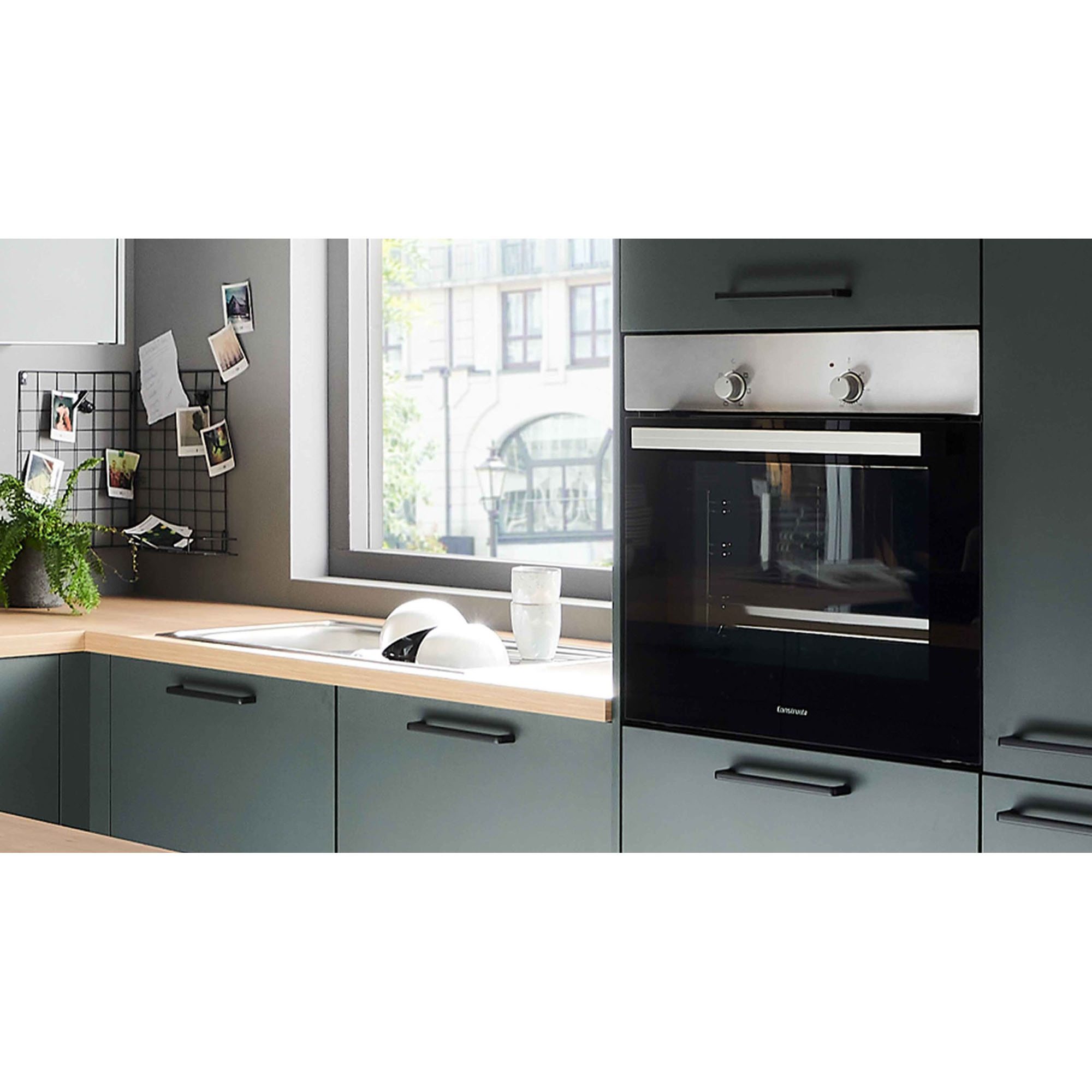 Ausschnitt mit Spüle vor dem Fenster und einem integrierten Backofen im Hochschrank rechts