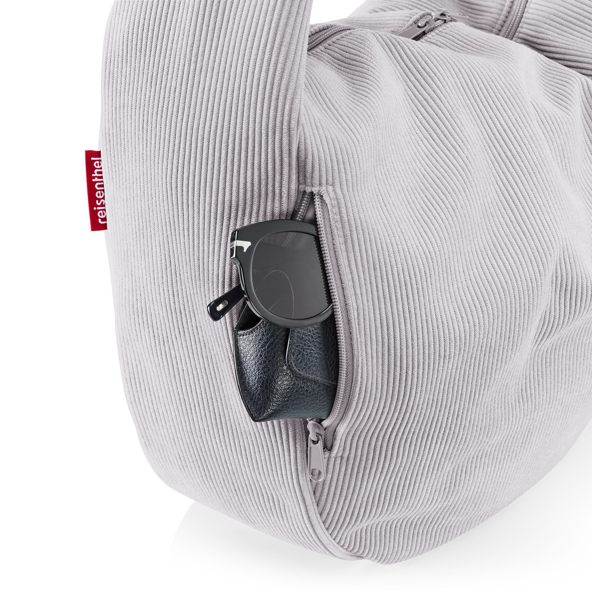 Detailaufnahme einer hellgrauen Reisenthel Cordtasche mit seitlichem Reißverschlussfach und Sonnenbrille