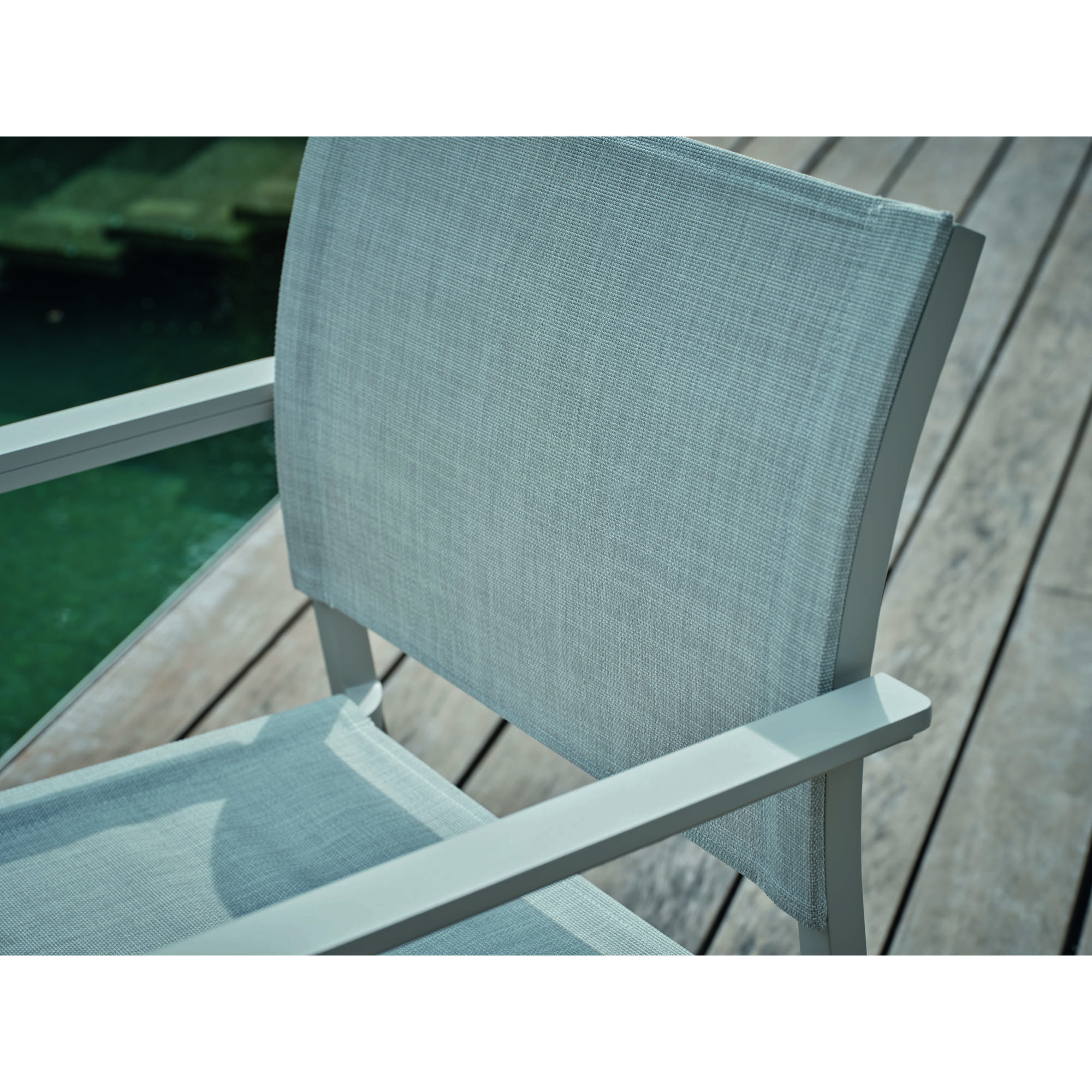 Detailaufnahme des textilen Rückenlehnenstoffs eines Gartenstuhls auf Holzterrasse
