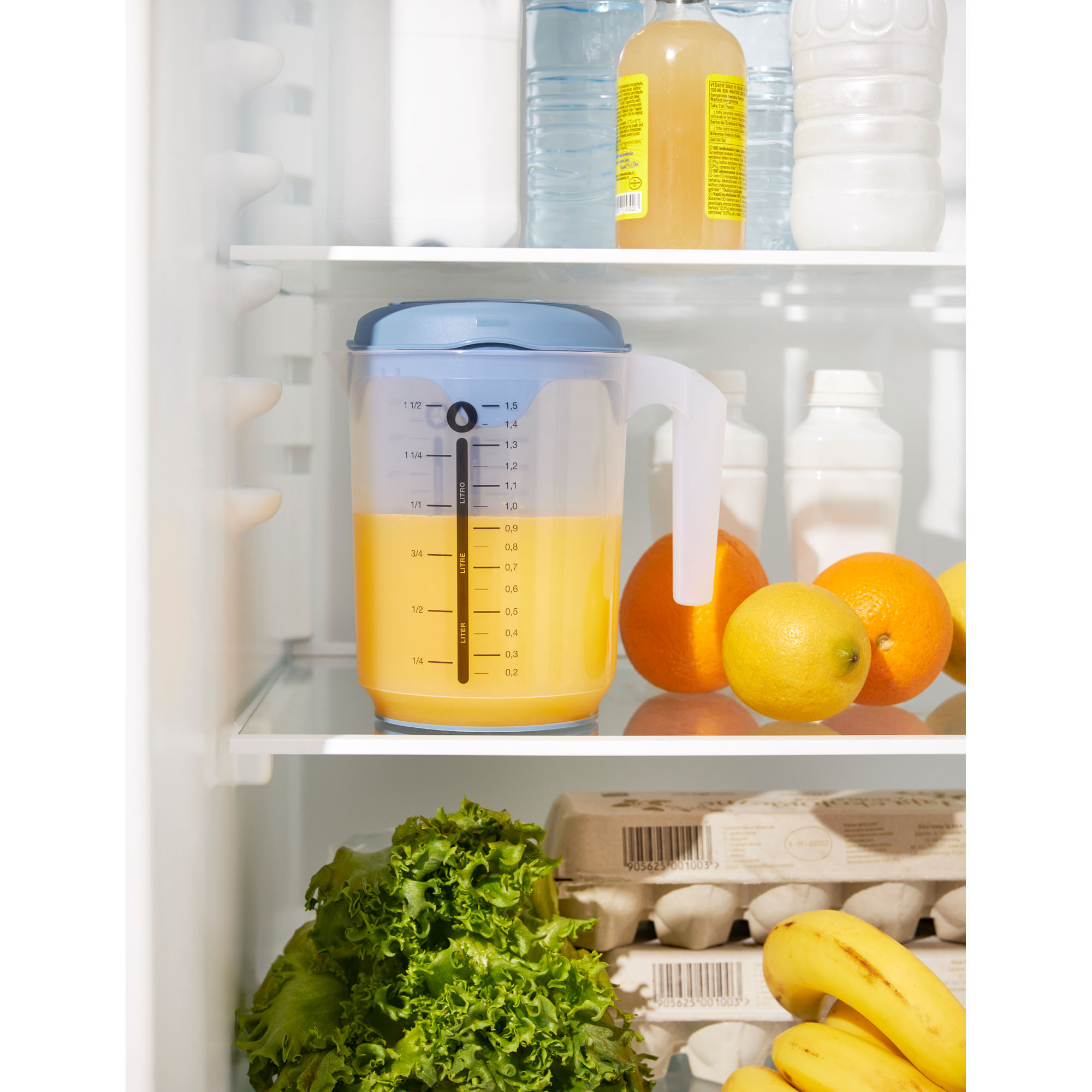 Transparenter Messbecher mit blauem Deckel auf einer Ablage im Kühlschrank
