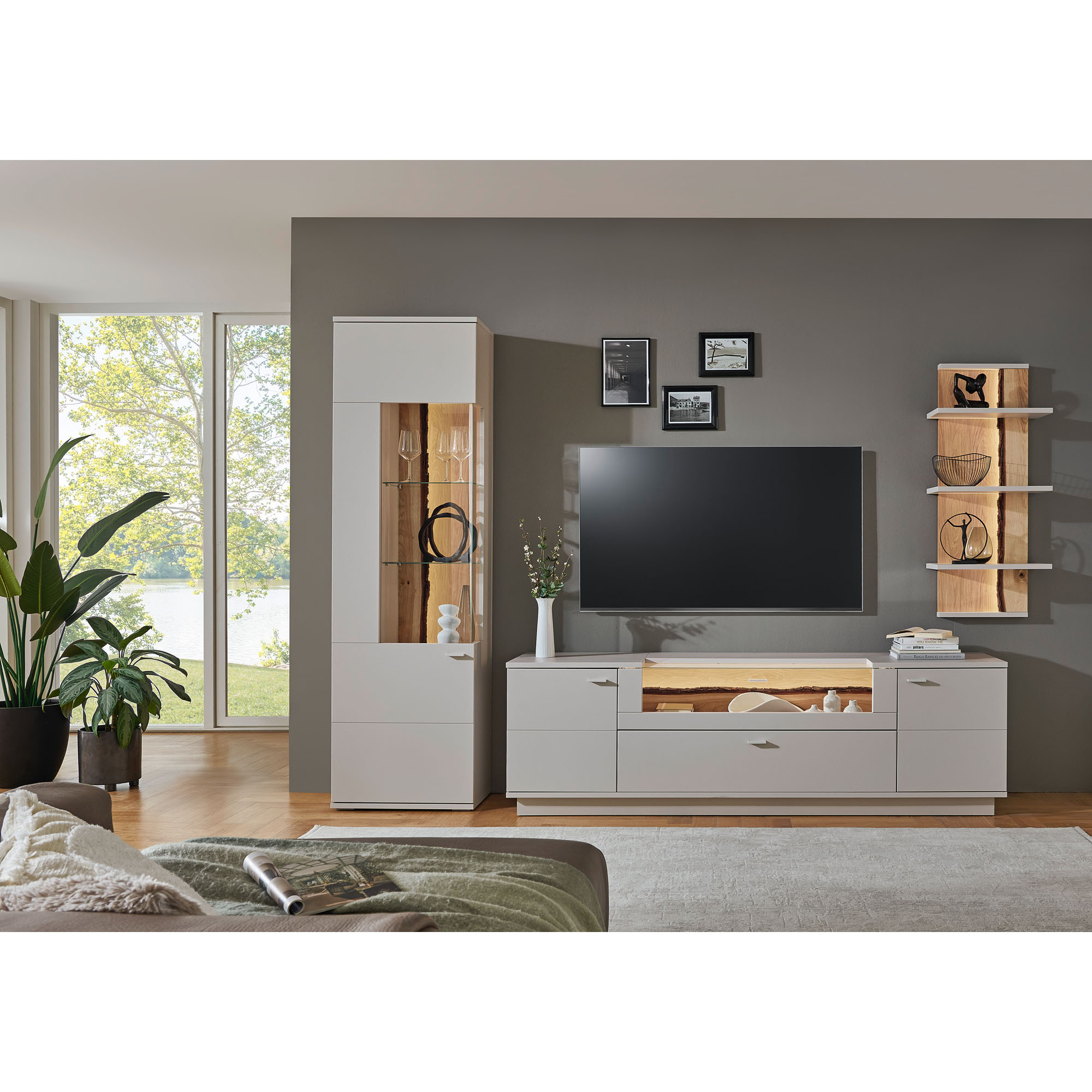 Wohnkombination mit beleuchtetem Hochschrank TV-Lowboard Fernseher und Wandregalen in einem hell eingerichteten Wohnzimmer
