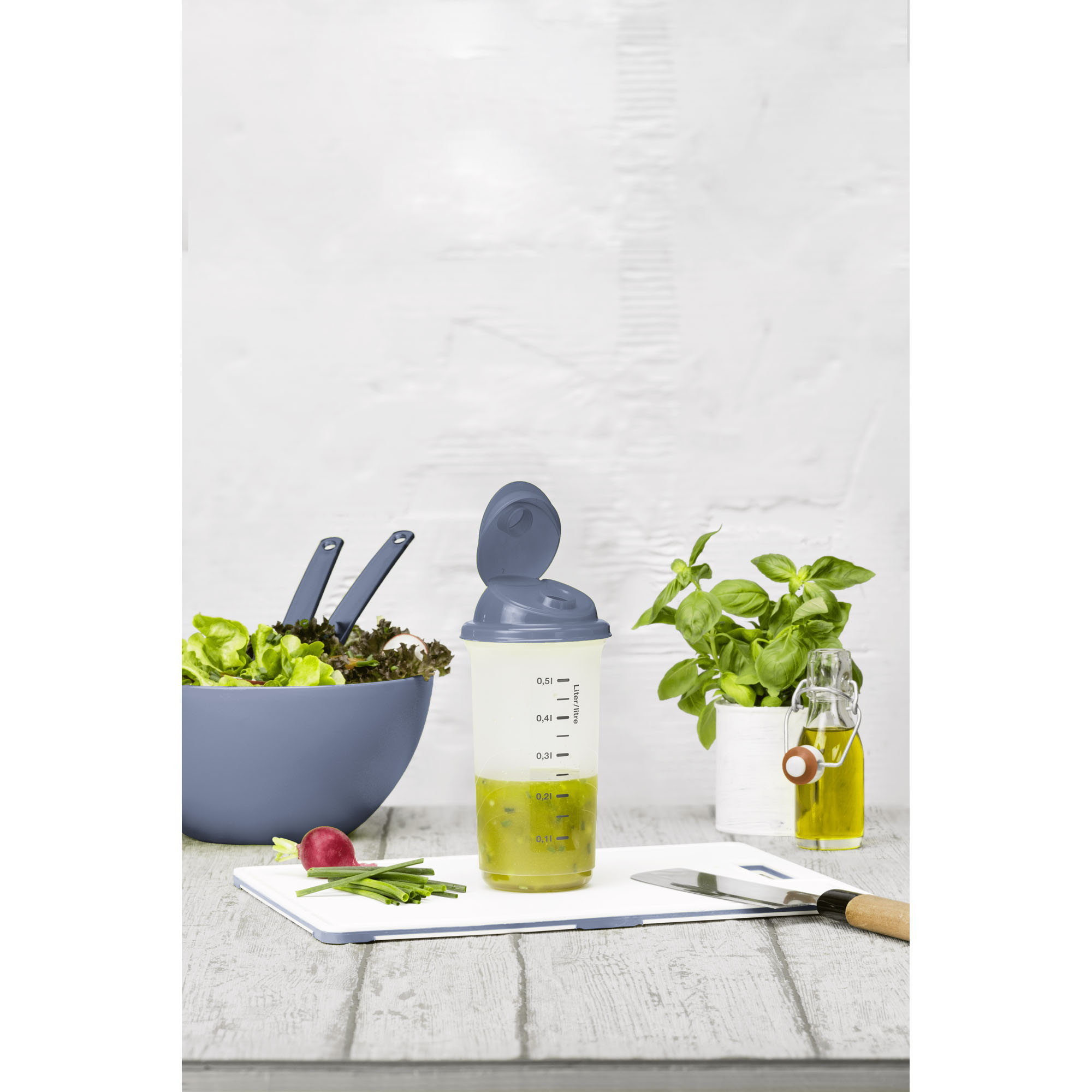Transparenter Shaker mit blauem Deckel auf einer Küchenarbeitsplatte neben Zutaten