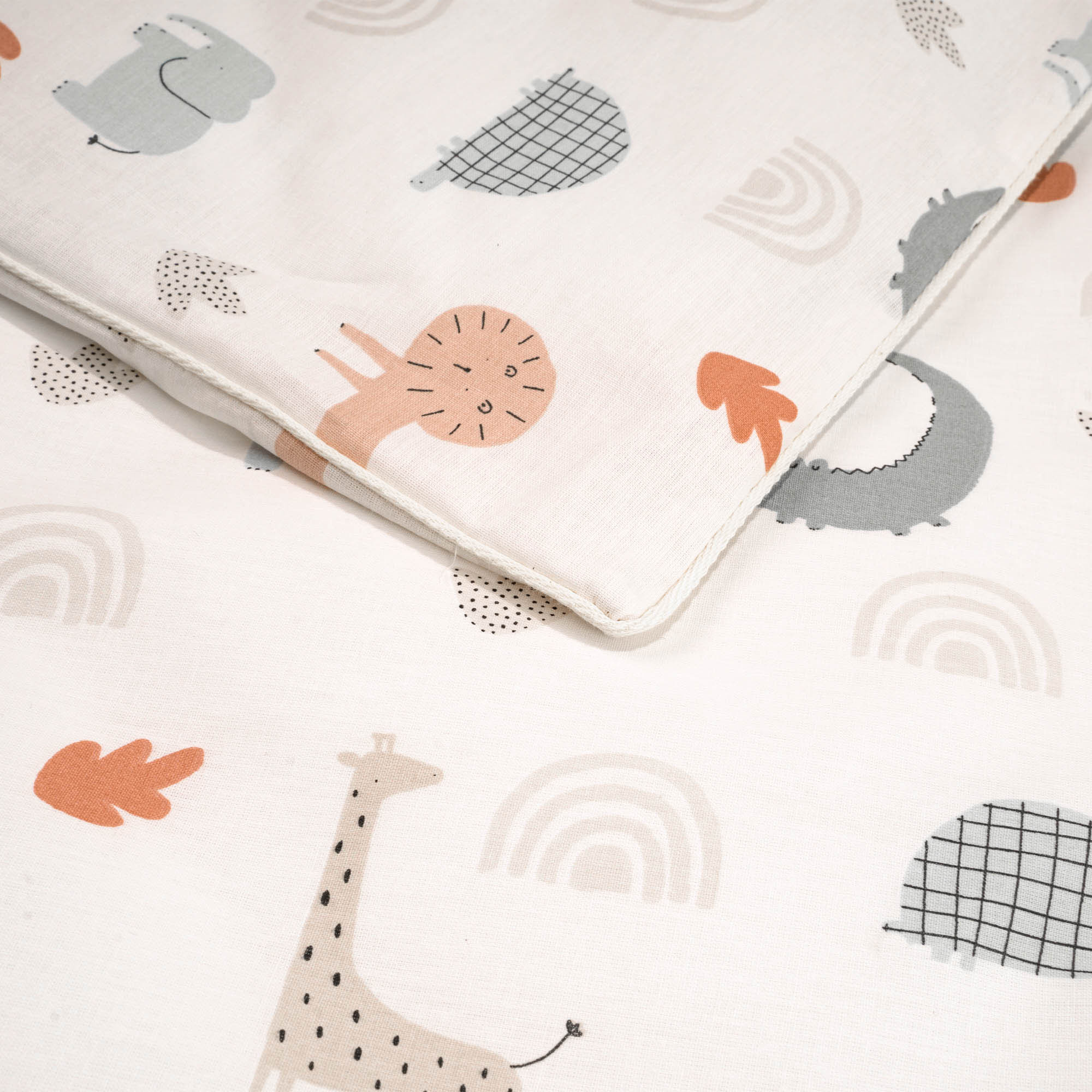 Nahaufnahme des Stoffes der Kinderbettwäsche mit Motiven wie Löwe, Giraffe und Regenbogen