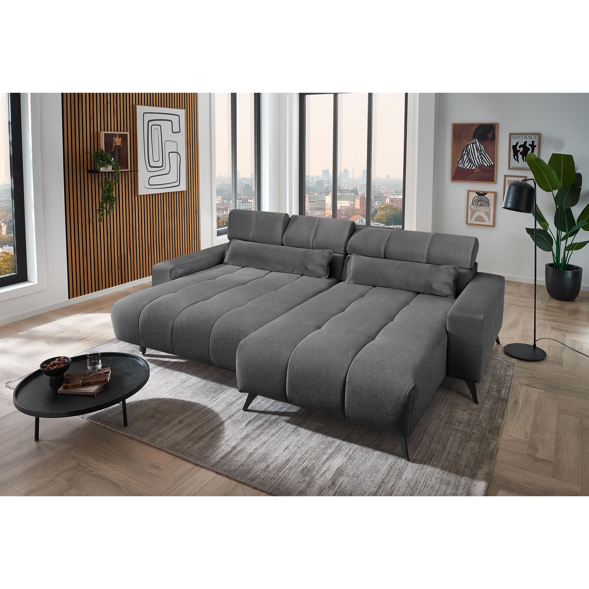 Dunkelgraues Ecksofa mit Ottomane rechts und ausgezogener Liegefläche in einem modernen Wohnzimmer mit Teppich und Couchtisch