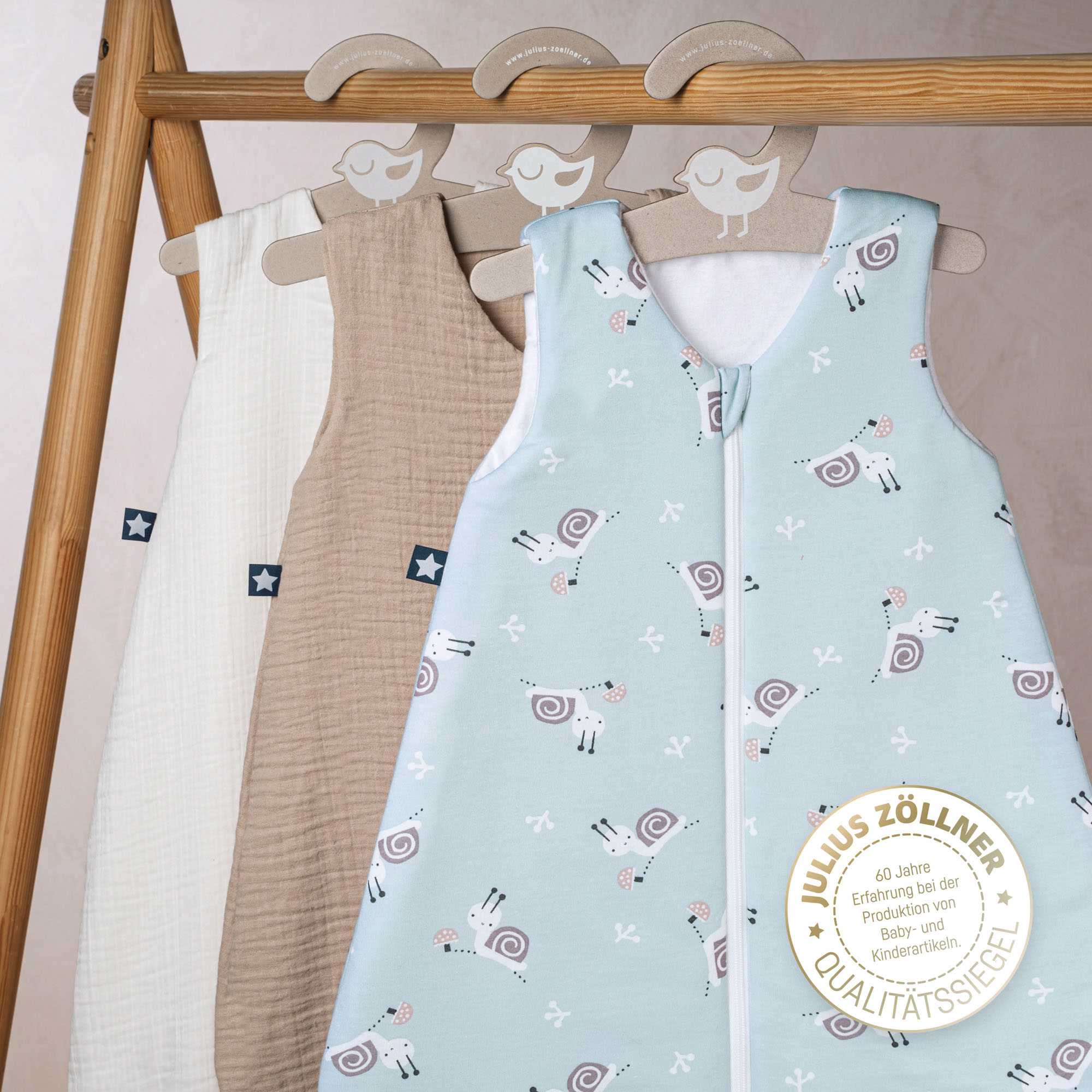 Hellblauer Babyschlafsack mit Tiermotiv hängend zwischen weiteren Schlafsäcken 