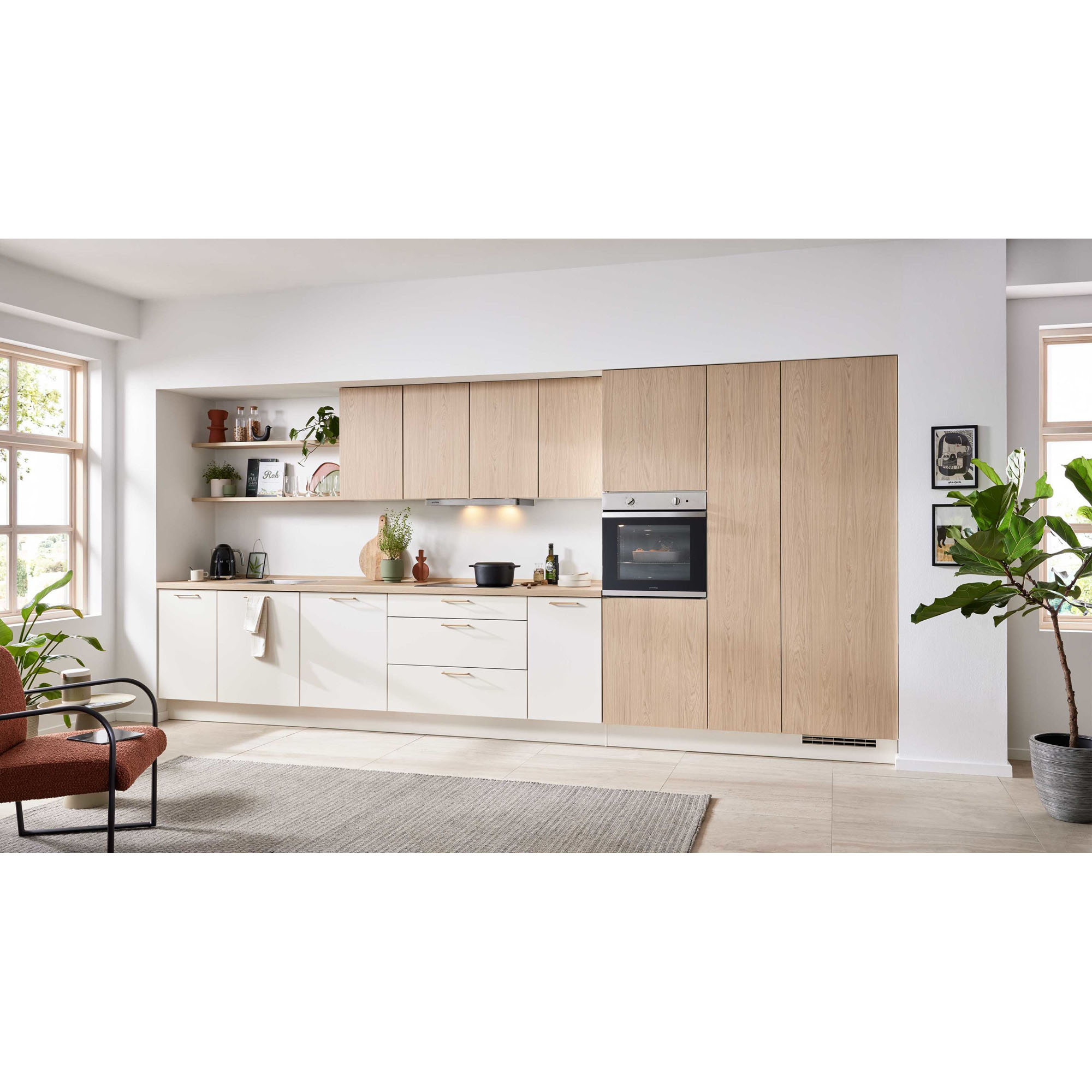 Moderne Küchenzeile in Weiß und heller Holzoptik mit großem Fenster und dekorativen Pflanzen