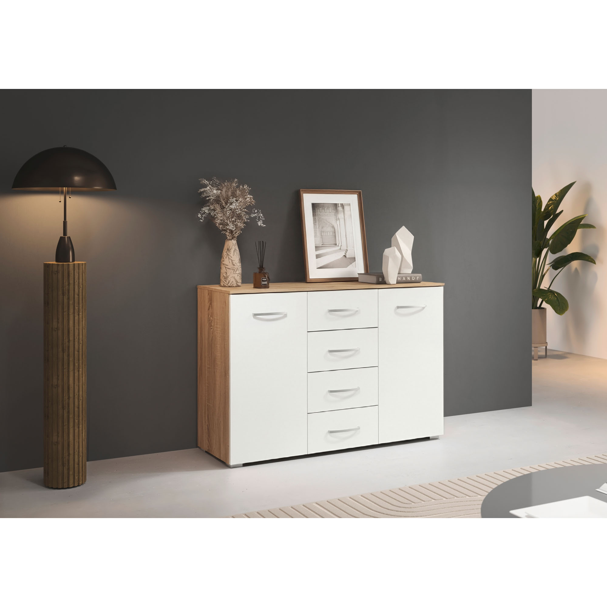 Weißes Sideboard mit Eiche Optik in modernem Wohnraum dekoriert mit Lampe Vase und Bildern auf dunkler Wand