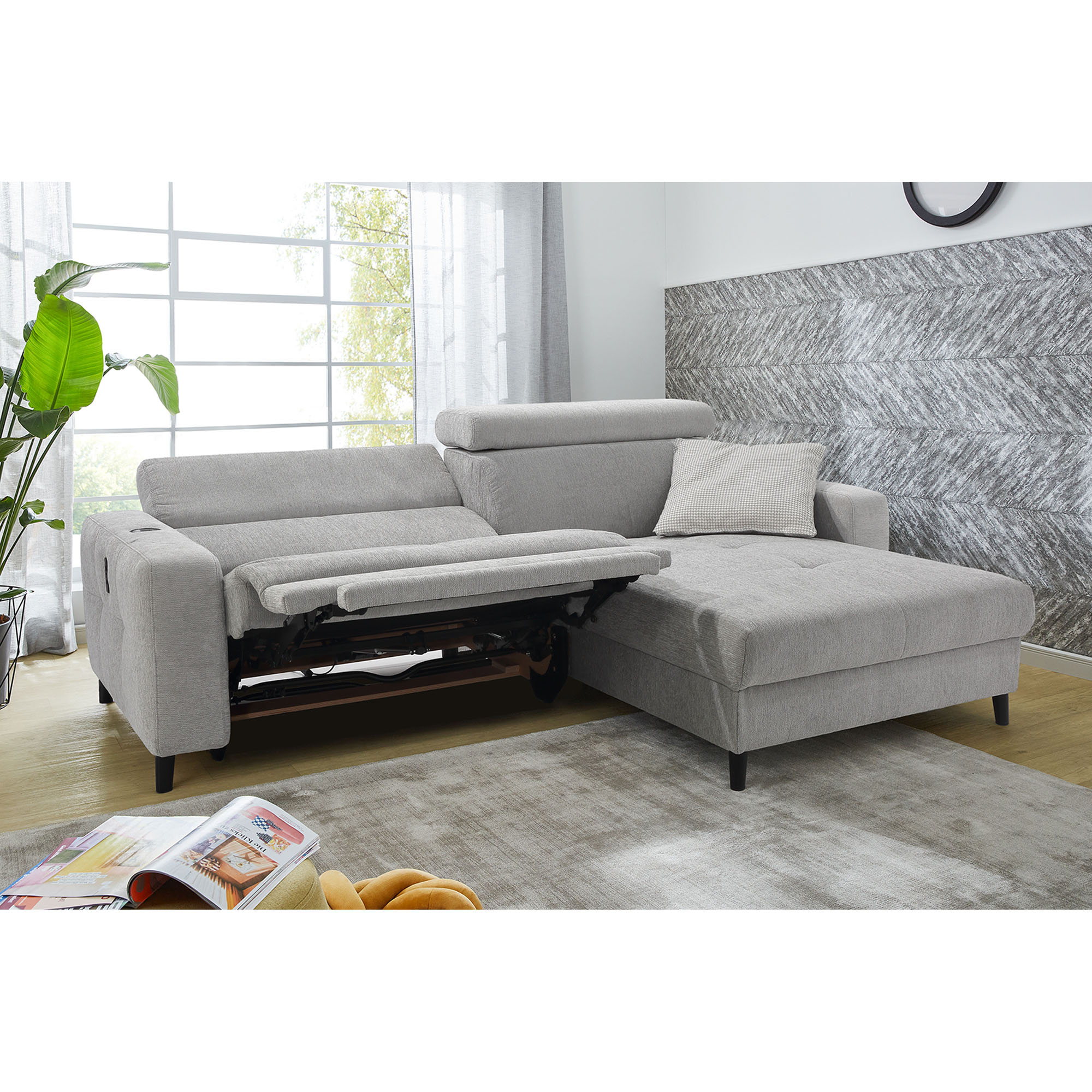 Hellgraues Ecksofa mit elektrischer Relaxfunktion und unterschiedlich verstellten Kopfstützen im Wohnzimmer