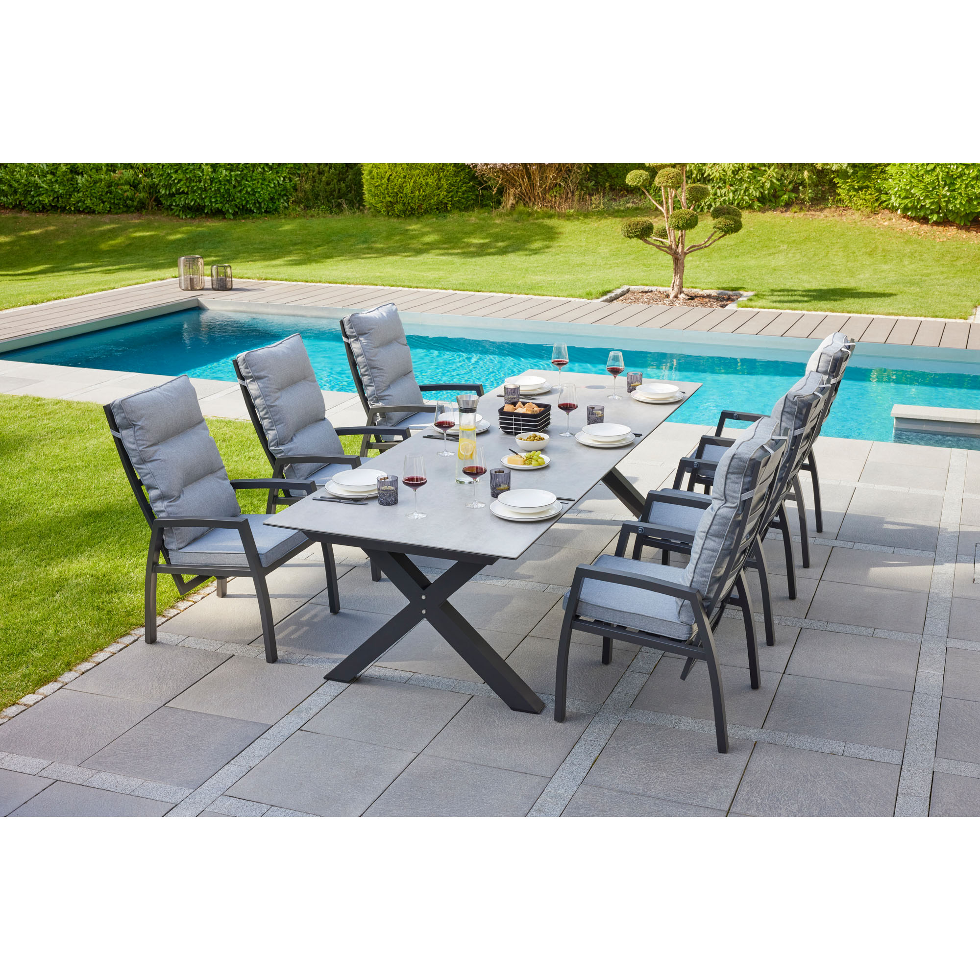 Gartentisch mit mehreren Gartenstühlen auf einer Terrasse neben einem Pool im Außenbereich