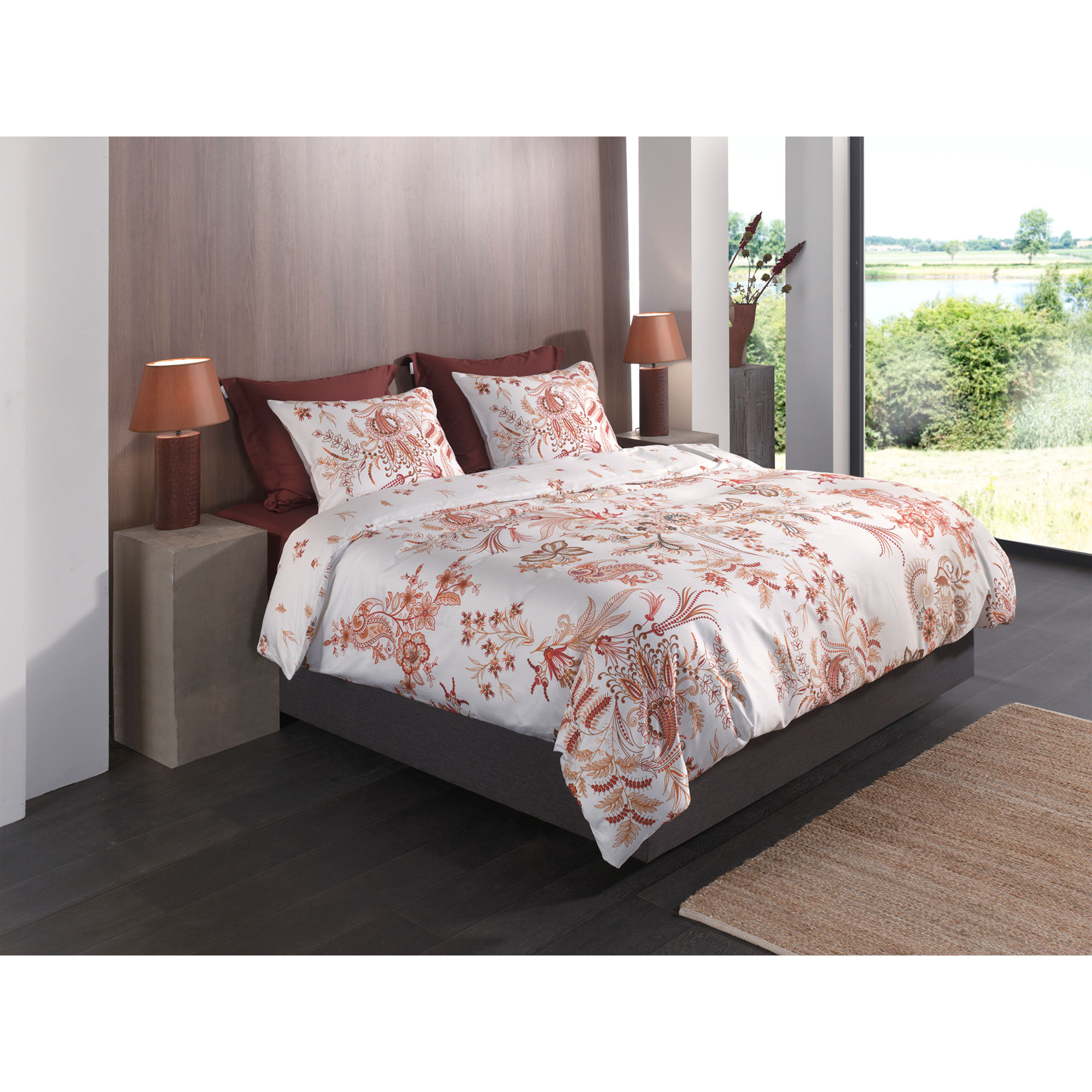 Bettwäsche Ceyda in White, 135 x 200 cm: bezogenes Bett in seitlicher Schlafzimmerszene mit filigranen roten, orangefarbenen und goldfarbenen Pflanzenmotiven auf weißem Grund.
