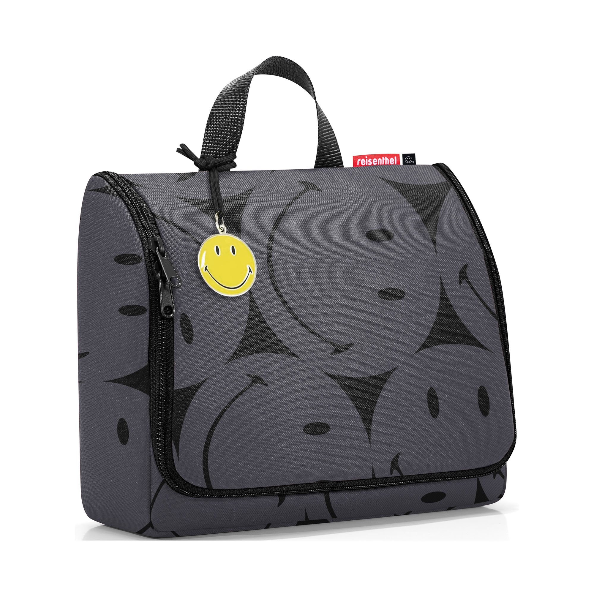 Kulturbeutel von Reisenthel, Modell Toiletbag XL, in Grau mit großflächigem Smiley-Muster, schräg von vorn geschlossen mit Tragegriff und Smiley-Anhänger.