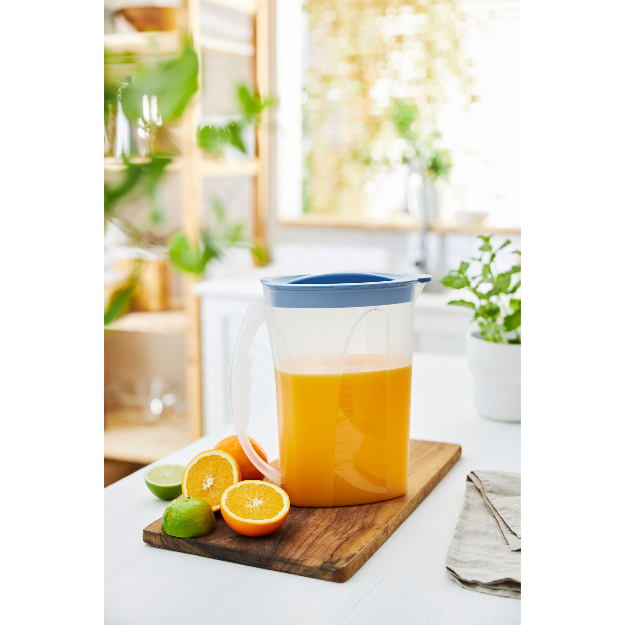 Transparente Kühlschrankkaraffe mit Getränk auf einer Arbeitsfläche neben Obst