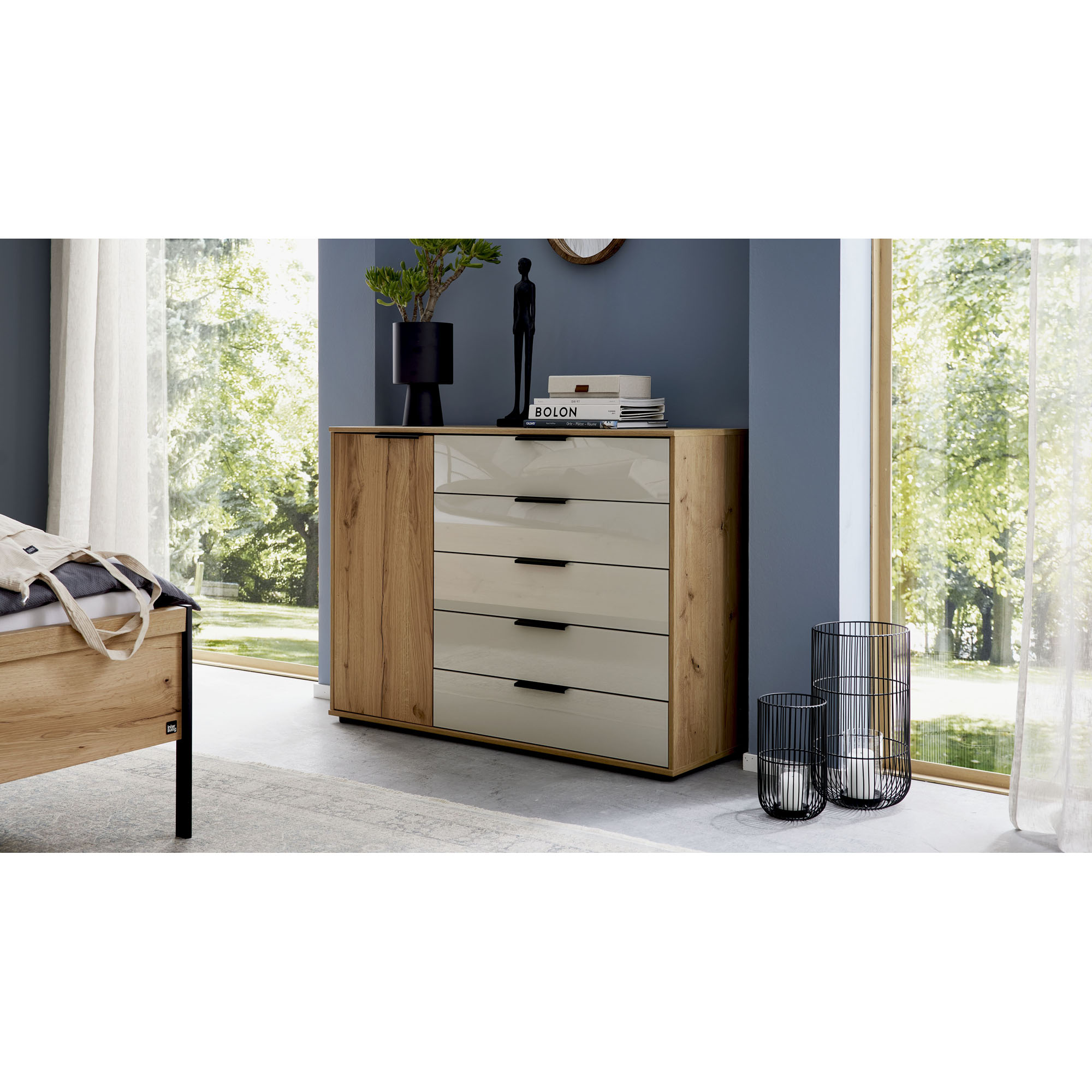 Interliving 1034 Kommode in Holzoptik mit Schubladen und Drehtür in einem modern eingerichteten Schlafzimmer