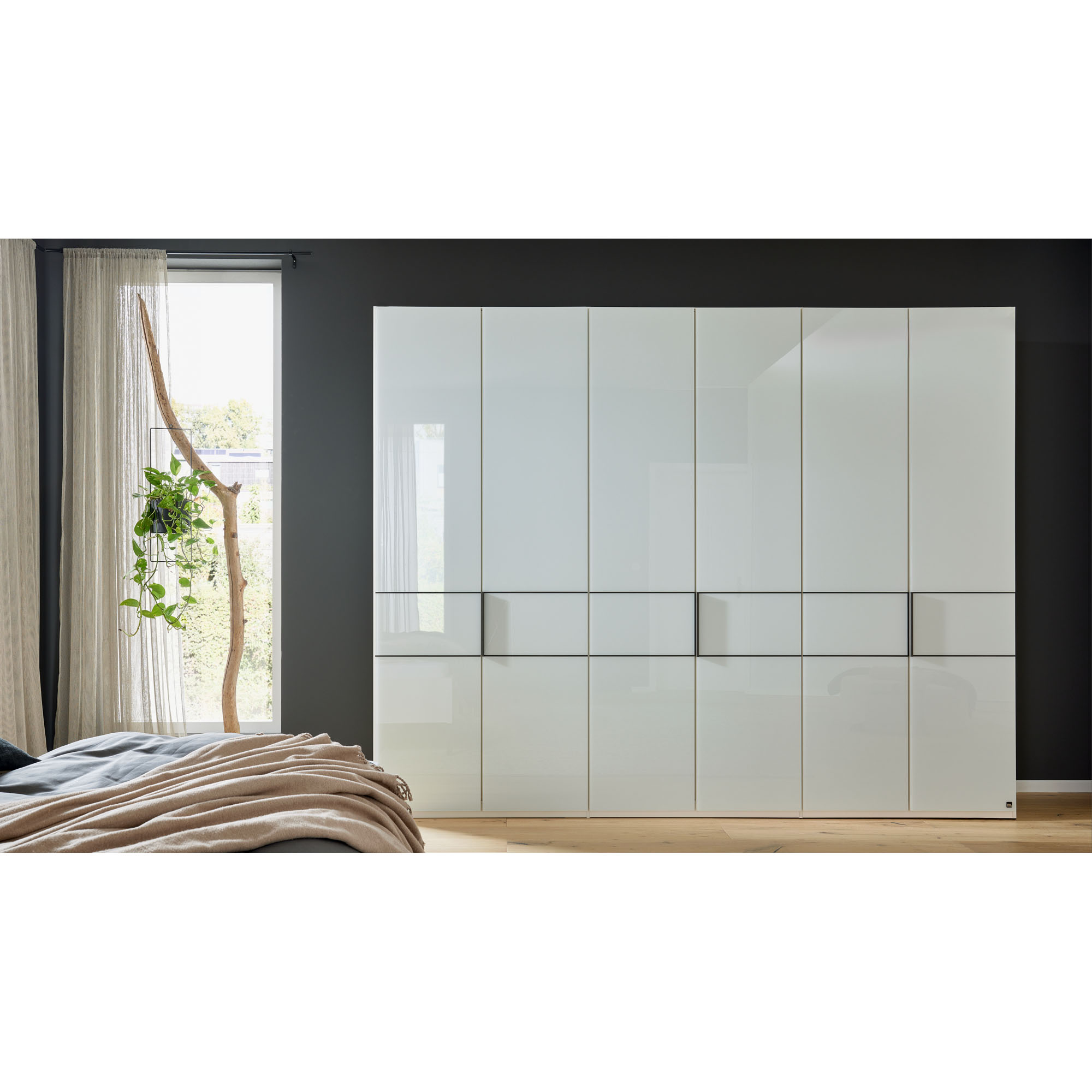 Weißer Kleiderschrank in einem Schlafzimmer mit Fenster und Bett im Vordergrund
