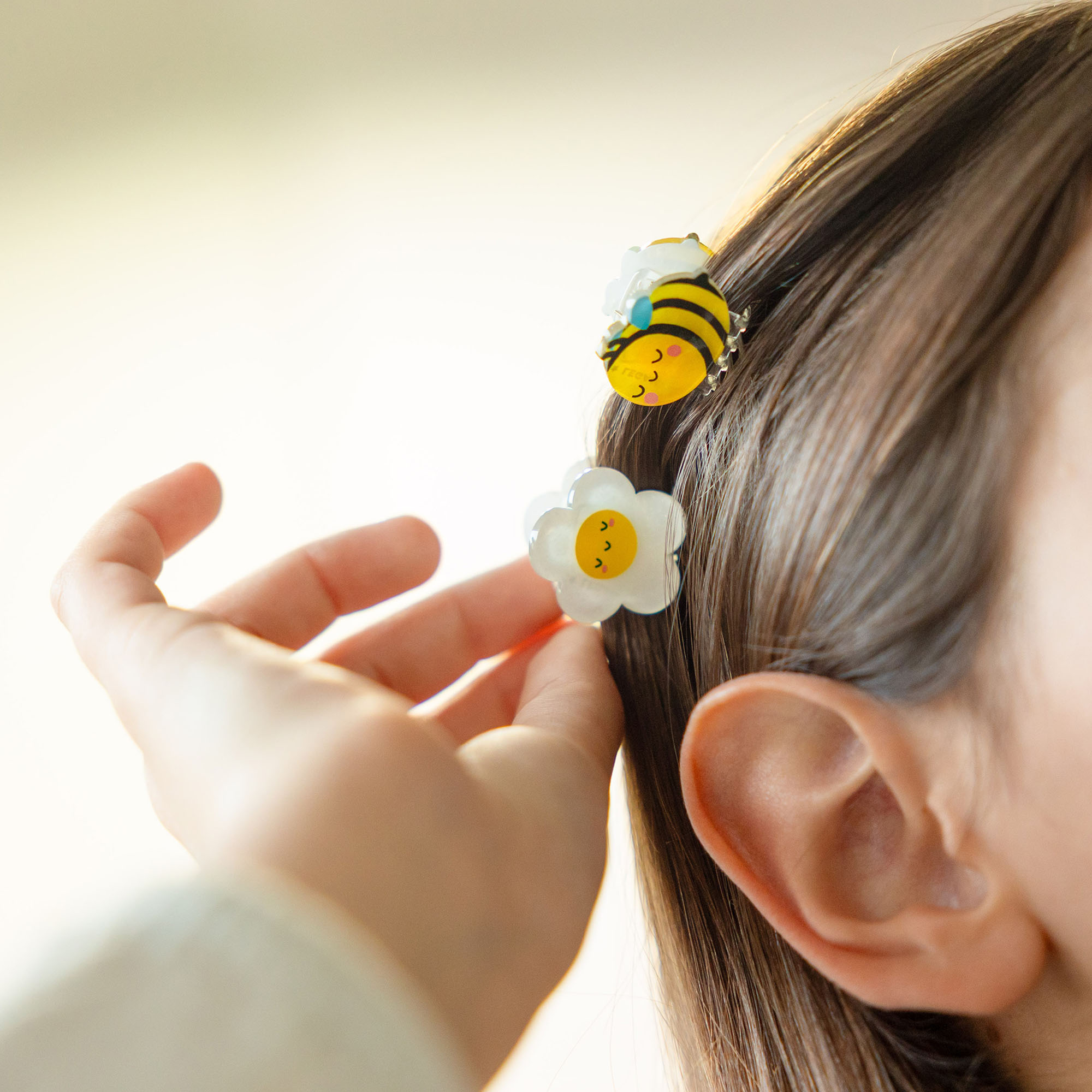Haarspangen-Set, 4 Stück – Biene von Legami: Hand befestigt Bienen-Haarspange im Haar eines Kindes.